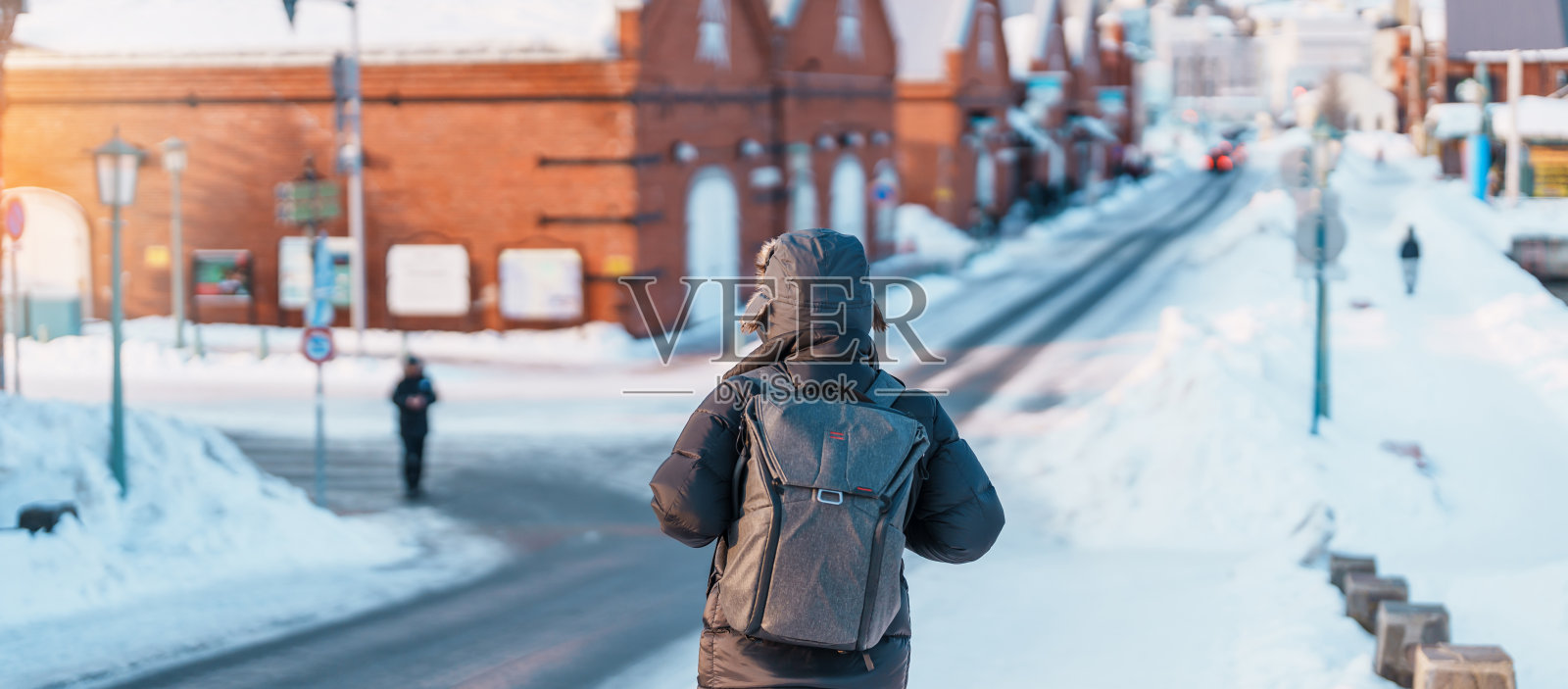 在函馆参观的男游客，穿着毛衣的游客在冬天的雪中游览金森红砖仓库。它是日本北海道的地标和著名景点。旅游度假概念照片摄影图片