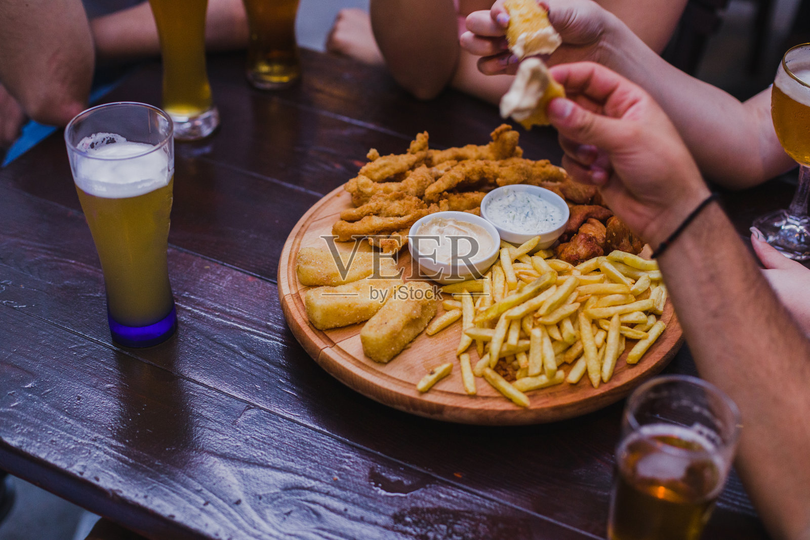 朋友们在酒吧里吃着鸡块和炸薯条，喝着精酿啤酒照片摄影图片