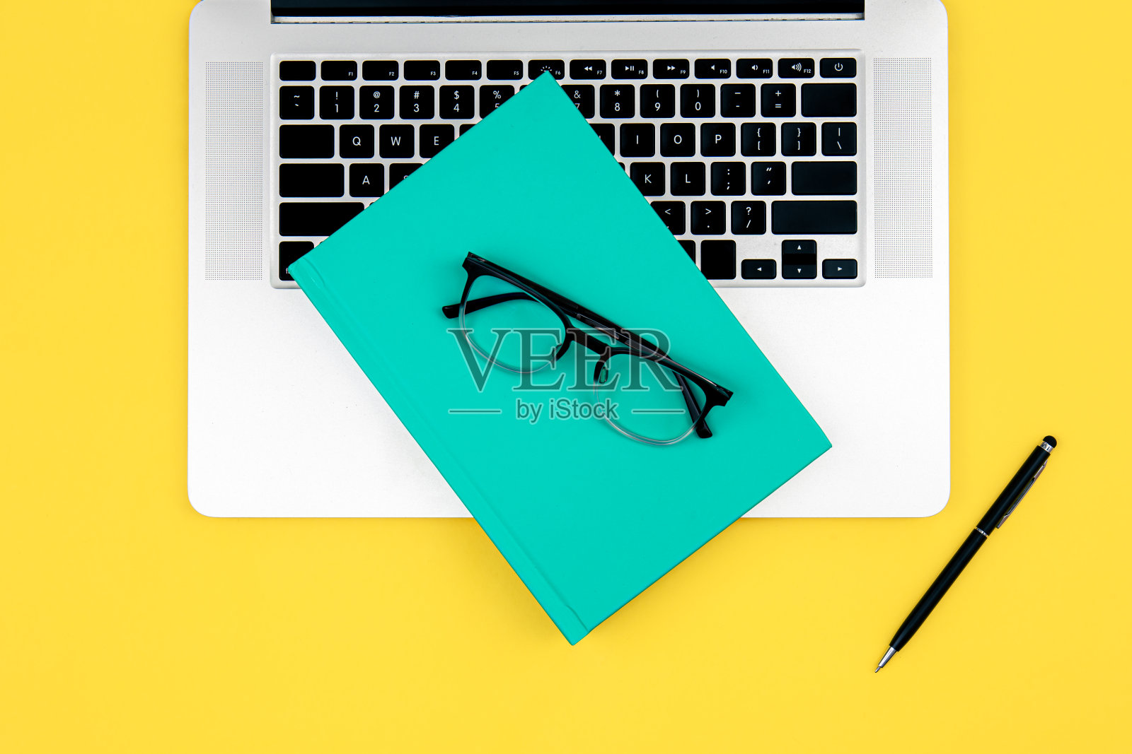 笔记本电脑，书和黄色背景的眼镜。照片摄影图片