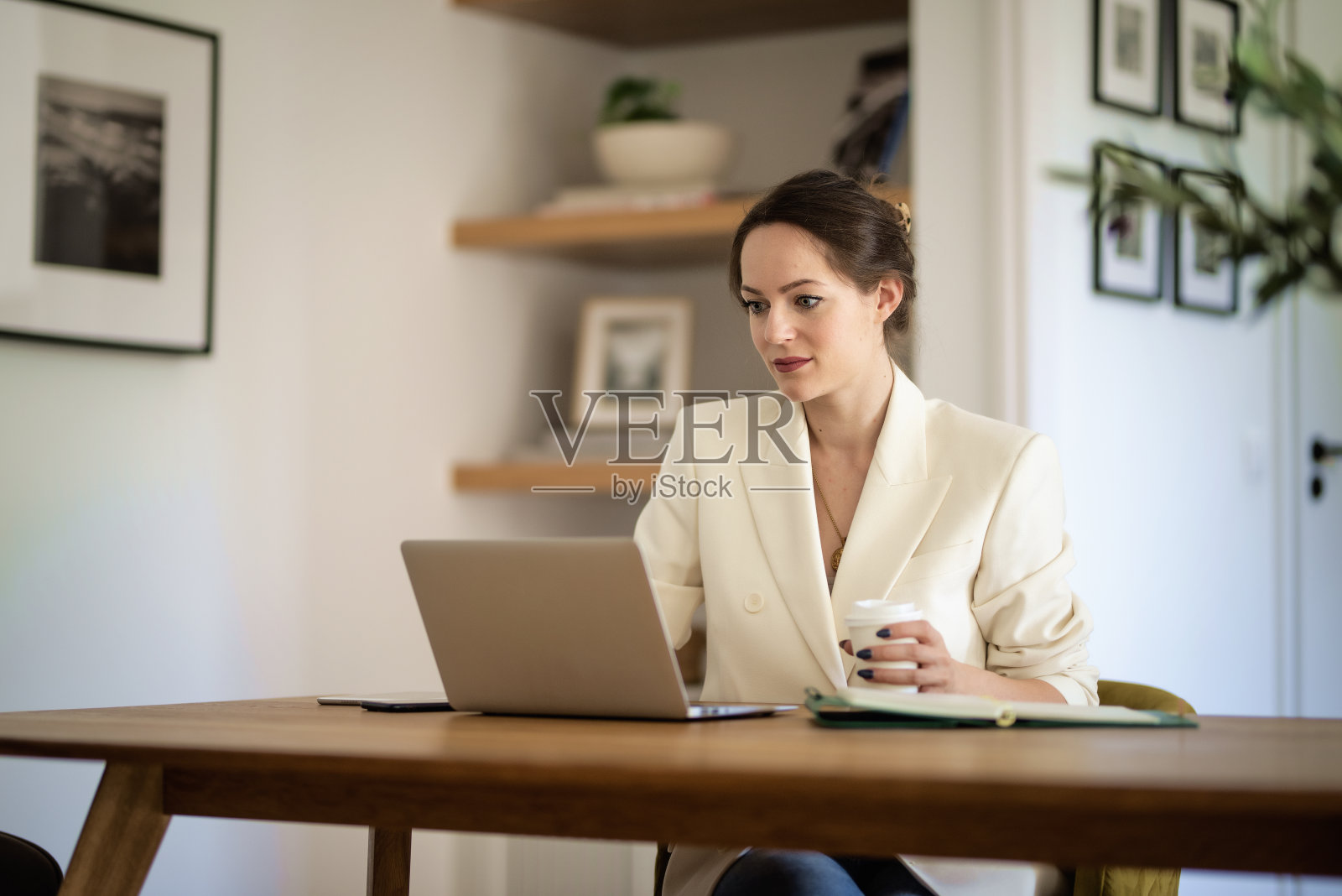 自信的年轻女子坐在桌边，在家里用笔记本电脑工作照片摄影图片