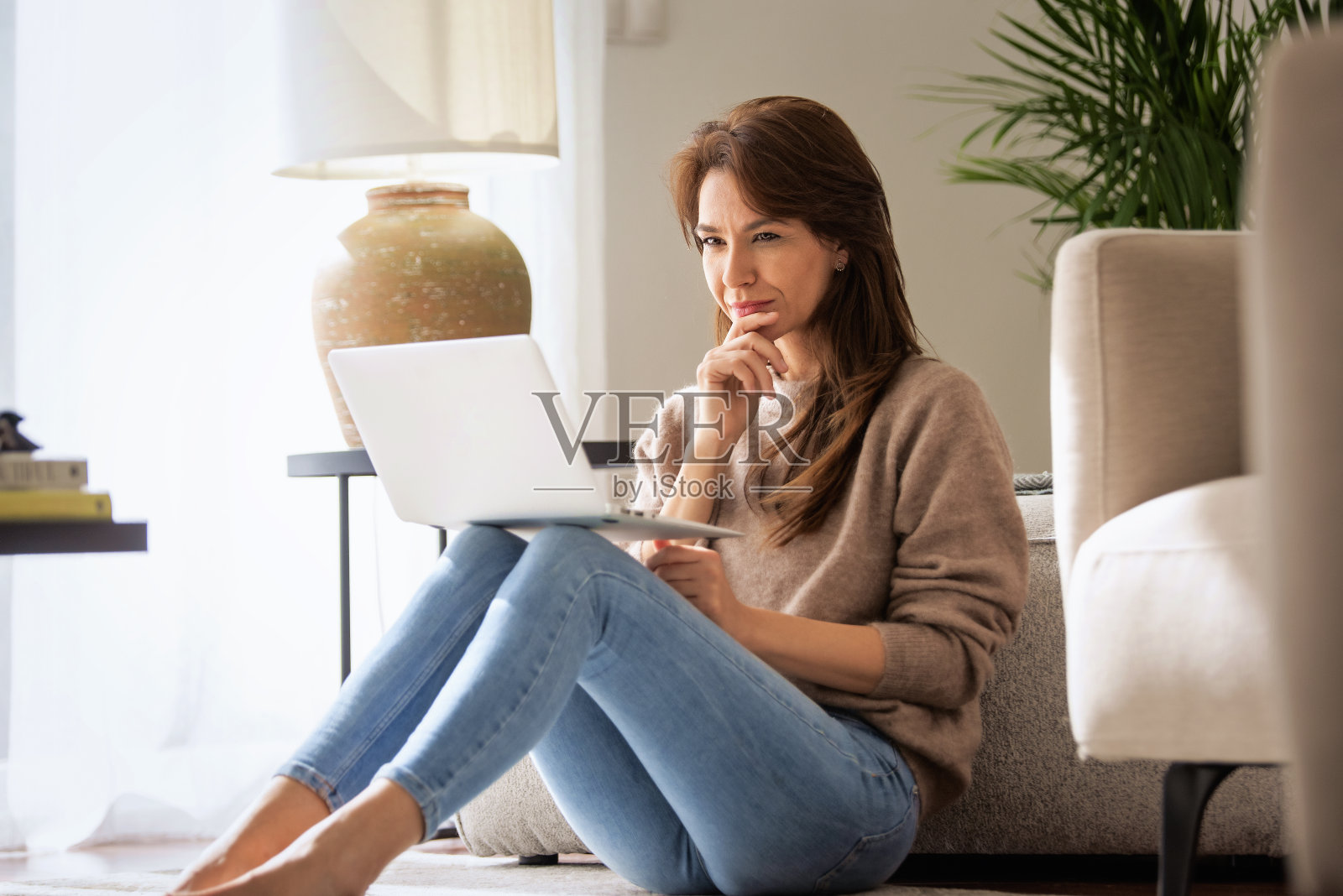 一个白人女人坐在家里的扶手椅上用着笔记本电脑照片摄影图片