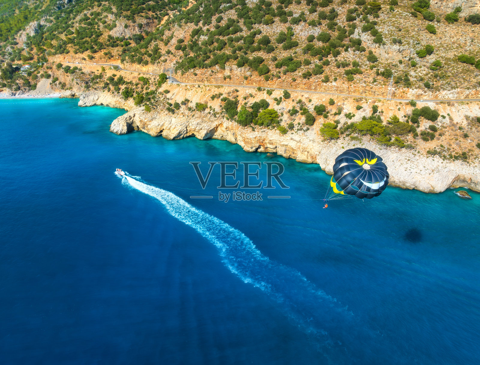 在土耳其奥卢德尼兹蔚蓝的海面上跳伞的鸟瞰图。夏季日落时的快艇、水和人们、山脉、海滩的俯视图。极端的假期。运动。旅行照片摄影图片