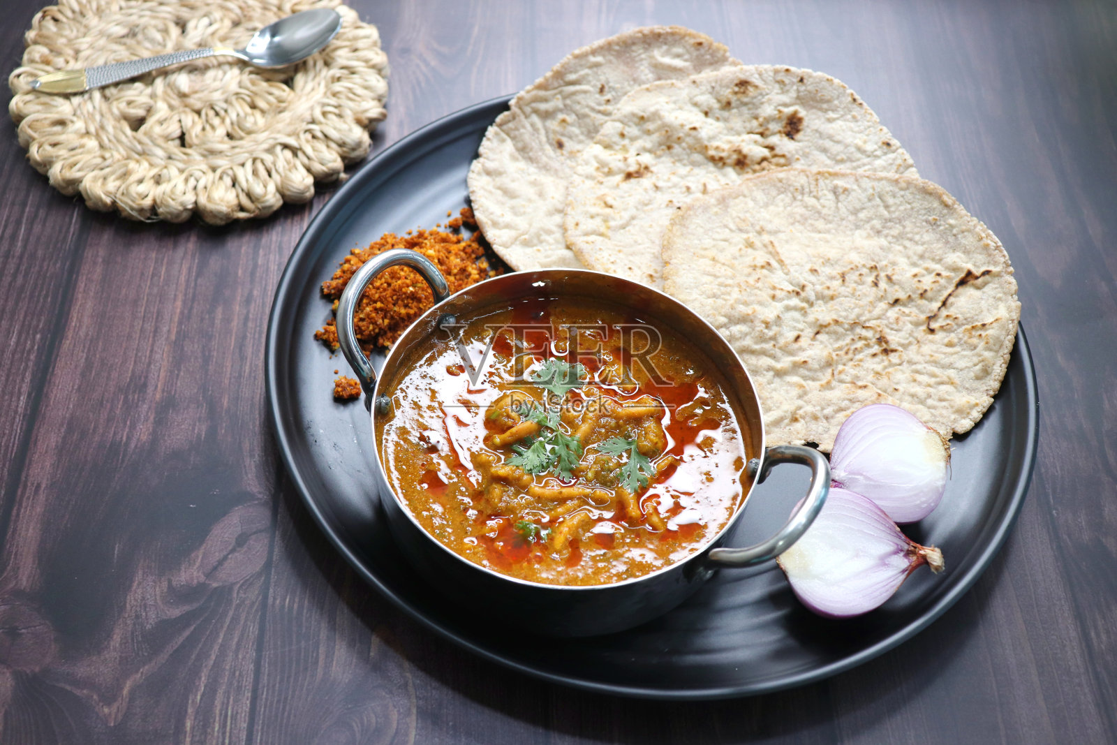 传统的Sev bhaji或Sev tamatar nu Shaak与Jowar Bhakri。Sev是一种酥脆的炸克粉。配上切碎的洋葱和柠檬。与复制空间。这是一种甜辣的印度咖喱。照片摄影图片