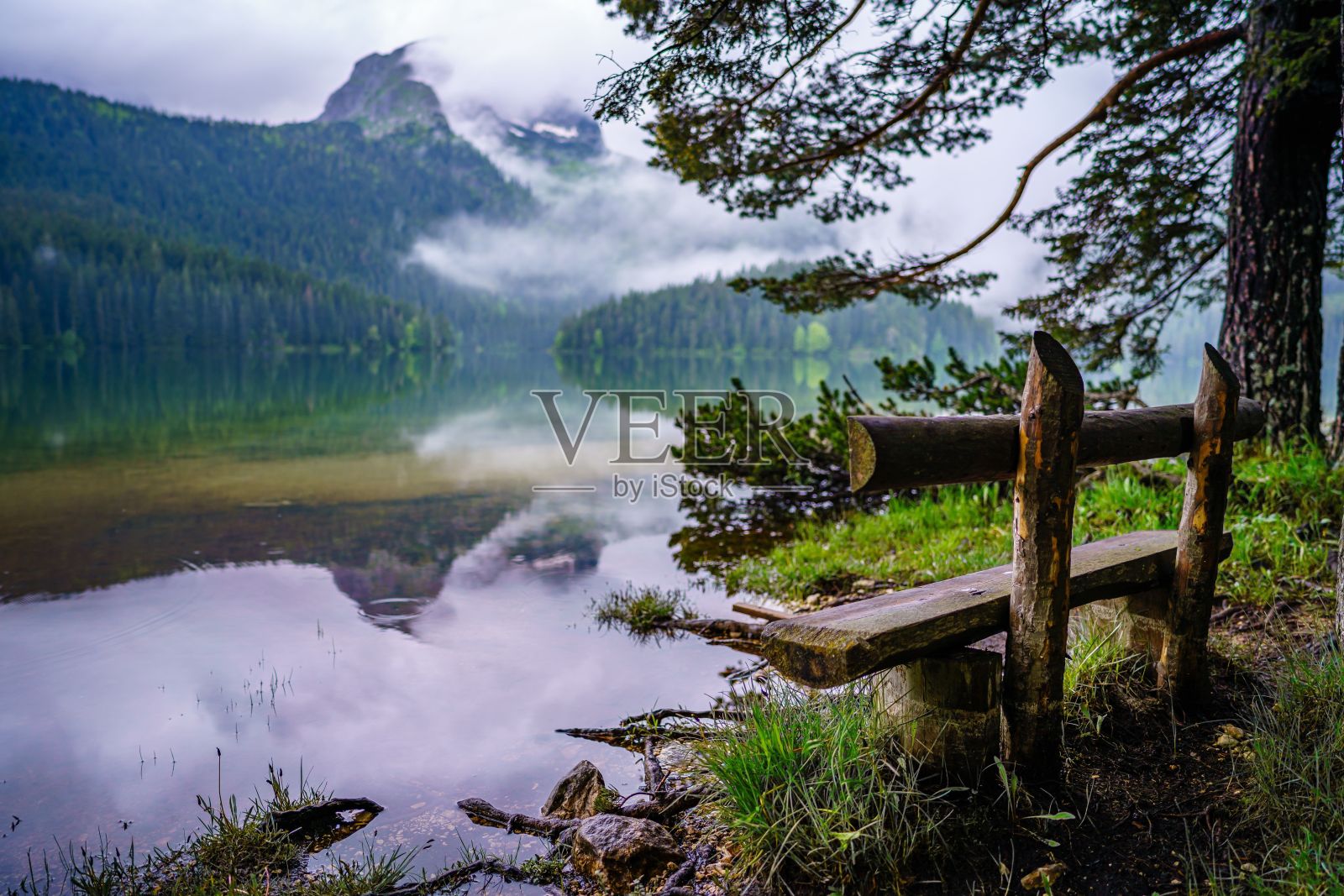 在黑山的杜密特国家公园，俯瞰湖泊和雄伟的多云山脉的旧长凳照片摄影图片