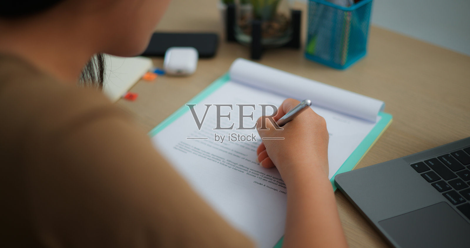 年轻的亚洲女性用笔记本电脑在桌子上写东西照片摄影图片