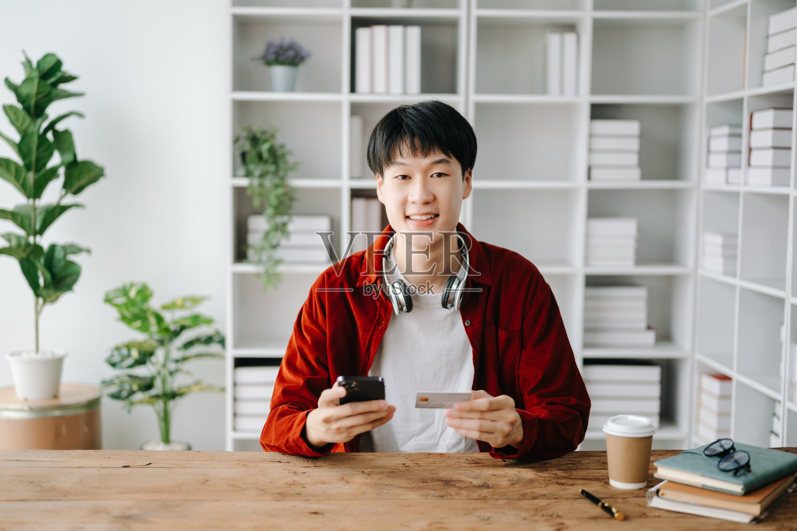 男人用智能手机进行移动支付，网上购物，全渠道，坐在桌子上照片摄影图片