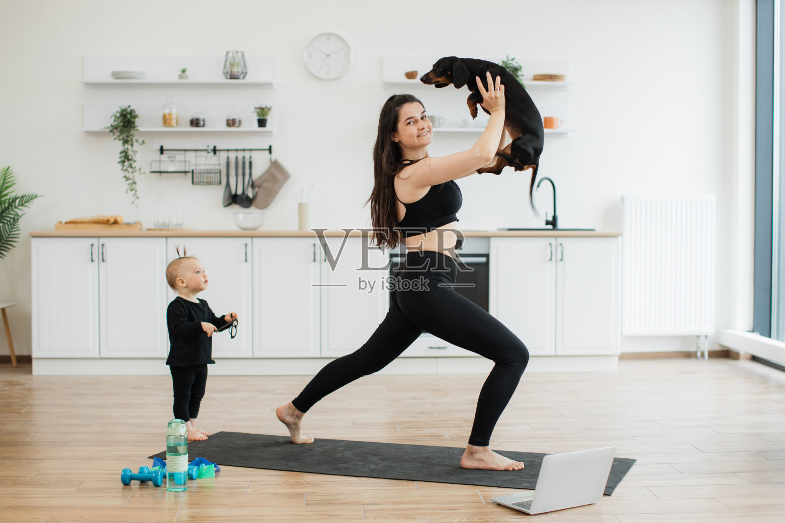 一名妇女带着狗在家里的女婴旁边做体式站着照片摄影图片