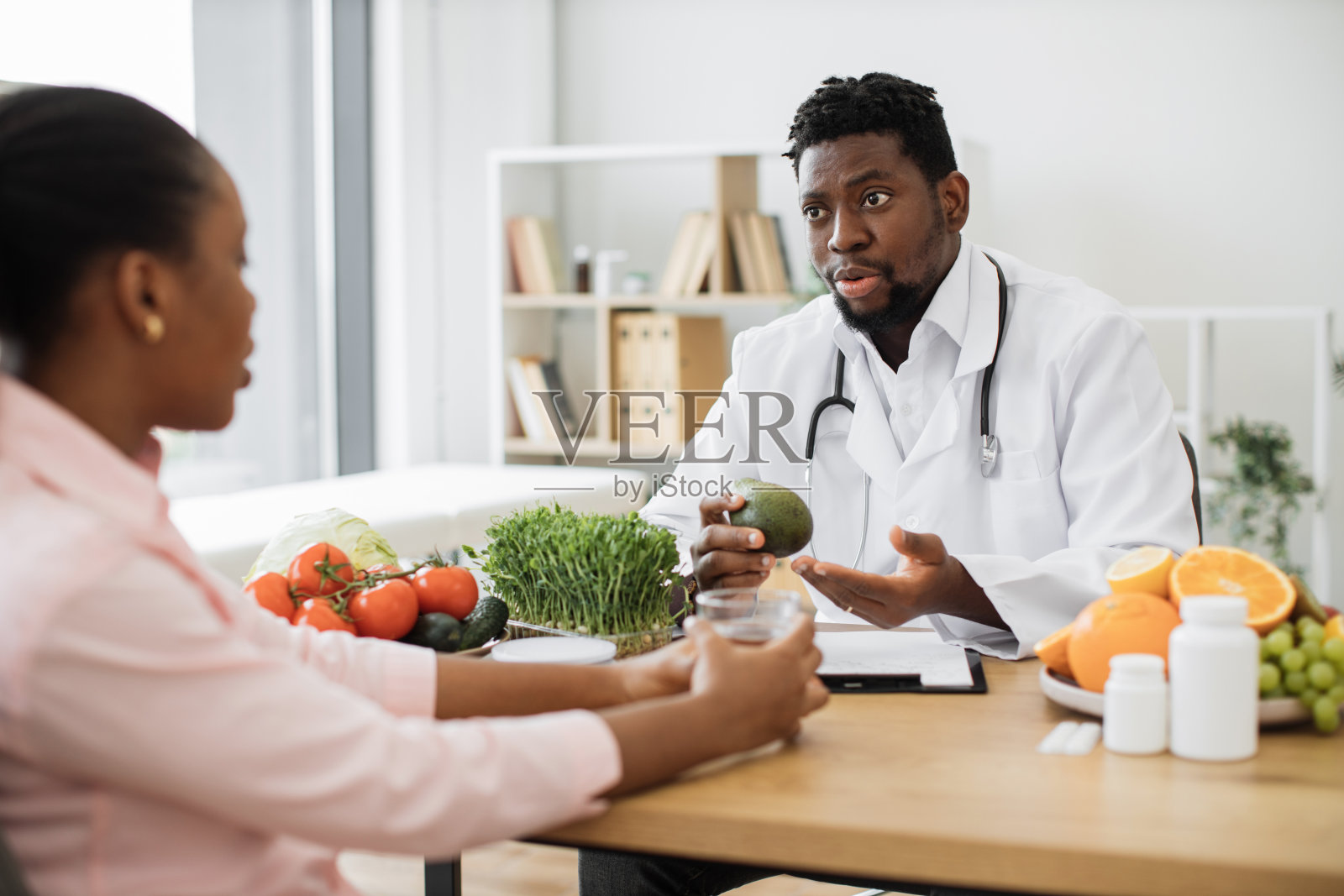 食品专家在诊所向女性客户展示微型蔬菜照片摄影图片