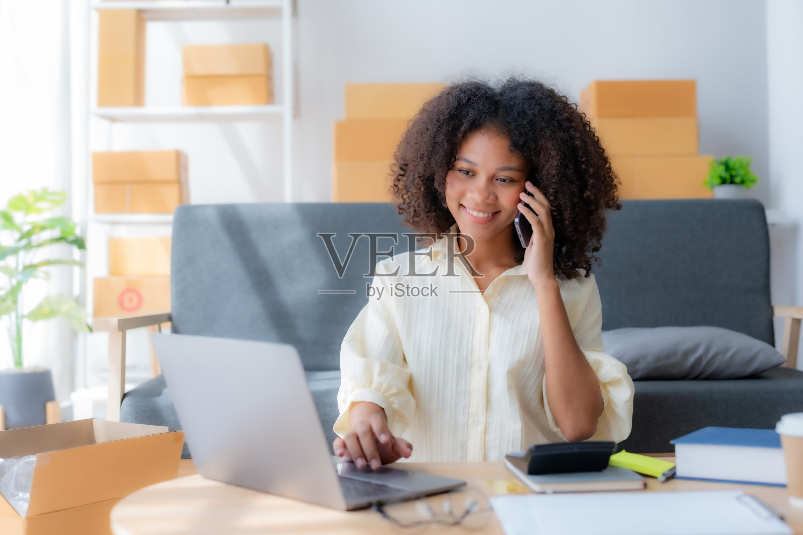 年轻的企业主一边用智能手机打电话，一边点菜。在家办公的女企业家通过电话确认订单。照片摄影图片