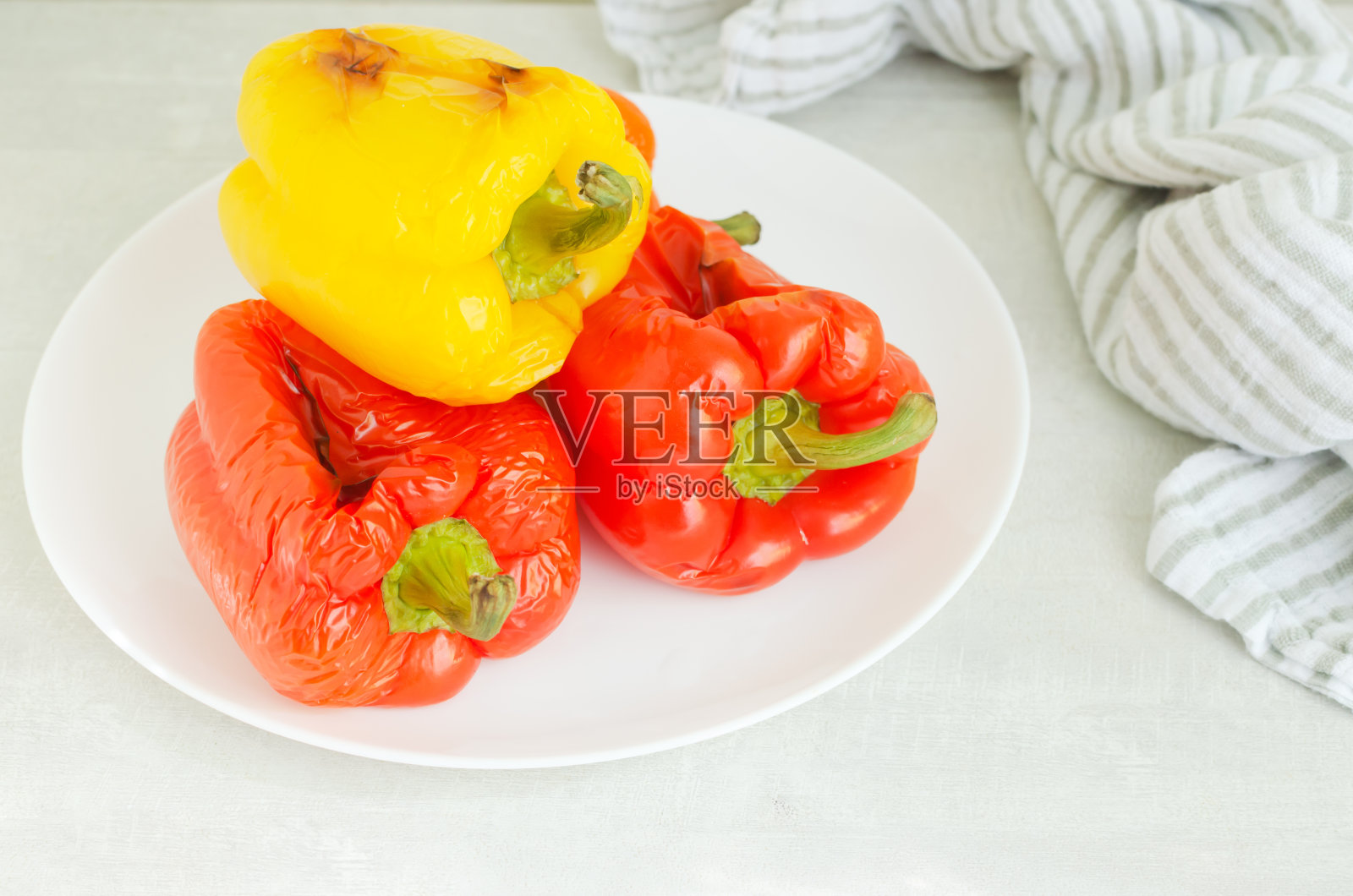 大红椒和大黄椒放在烤箱里的白色盘子里烤着。沙拉的配料。传统的意大利菜。素食和纯素食品。水平方向。照片摄影图片