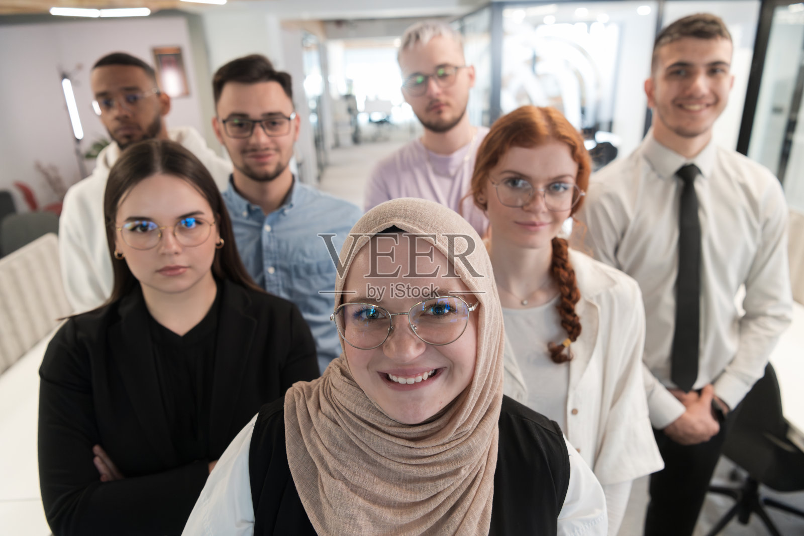 一群年轻的商务人士站在一起，从繁忙的工作日中休息一下，展示同志情谊，团队合作，在充满活力的工作场所放松一下照片摄影图片