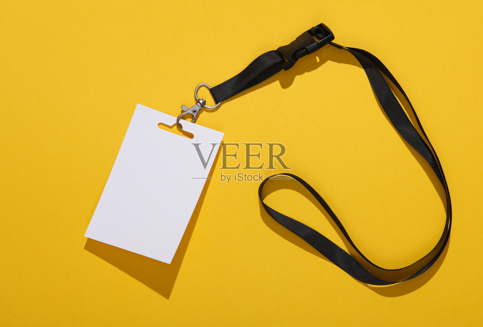 空白的白色身份证徽章模型与黑色腰带在黄色背景。员工身份、姓名标签。文字和设计的空间。照片摄影图片