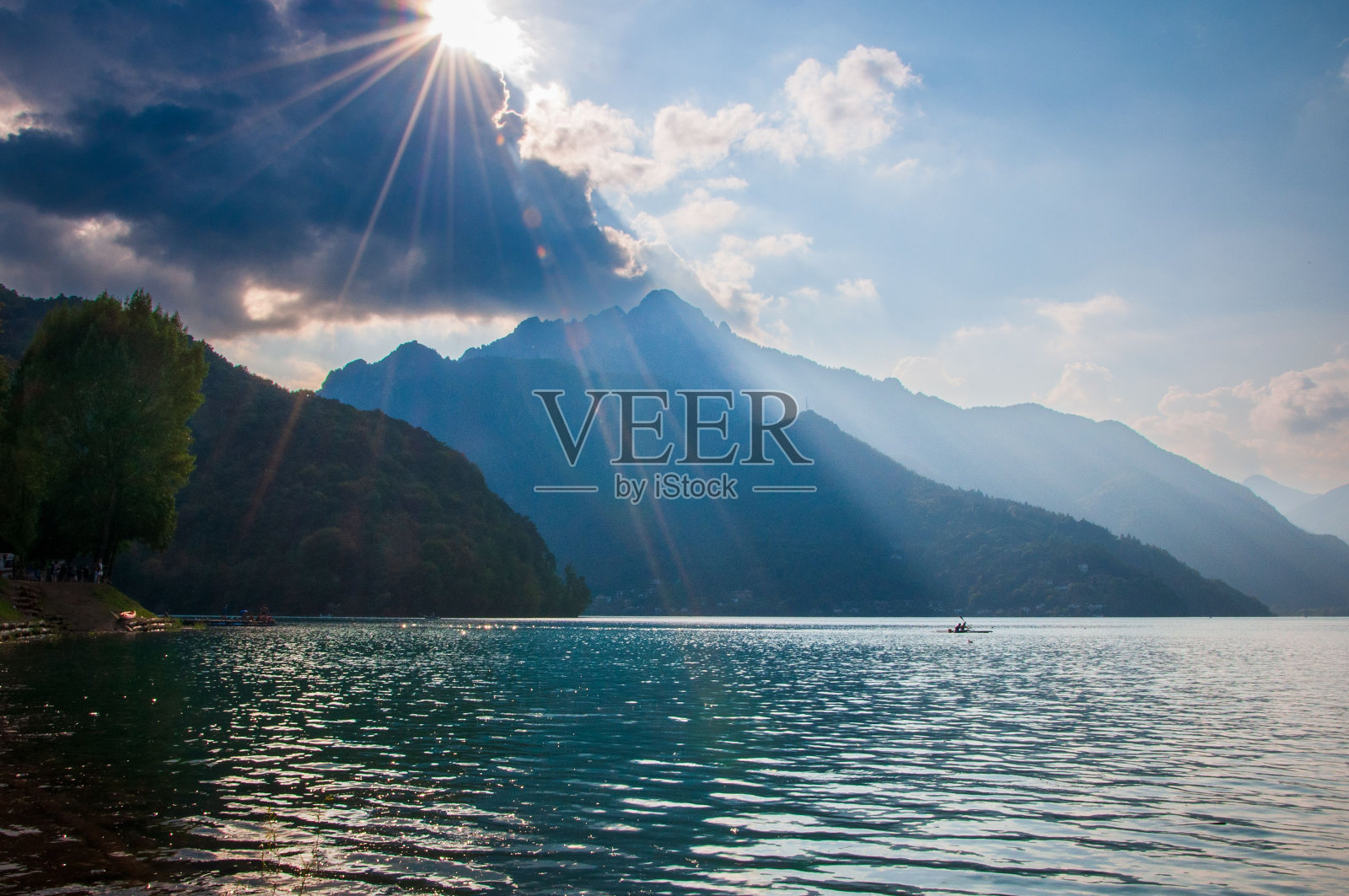 太阳从莱德罗湖的云层后面照出来照片摄影图片