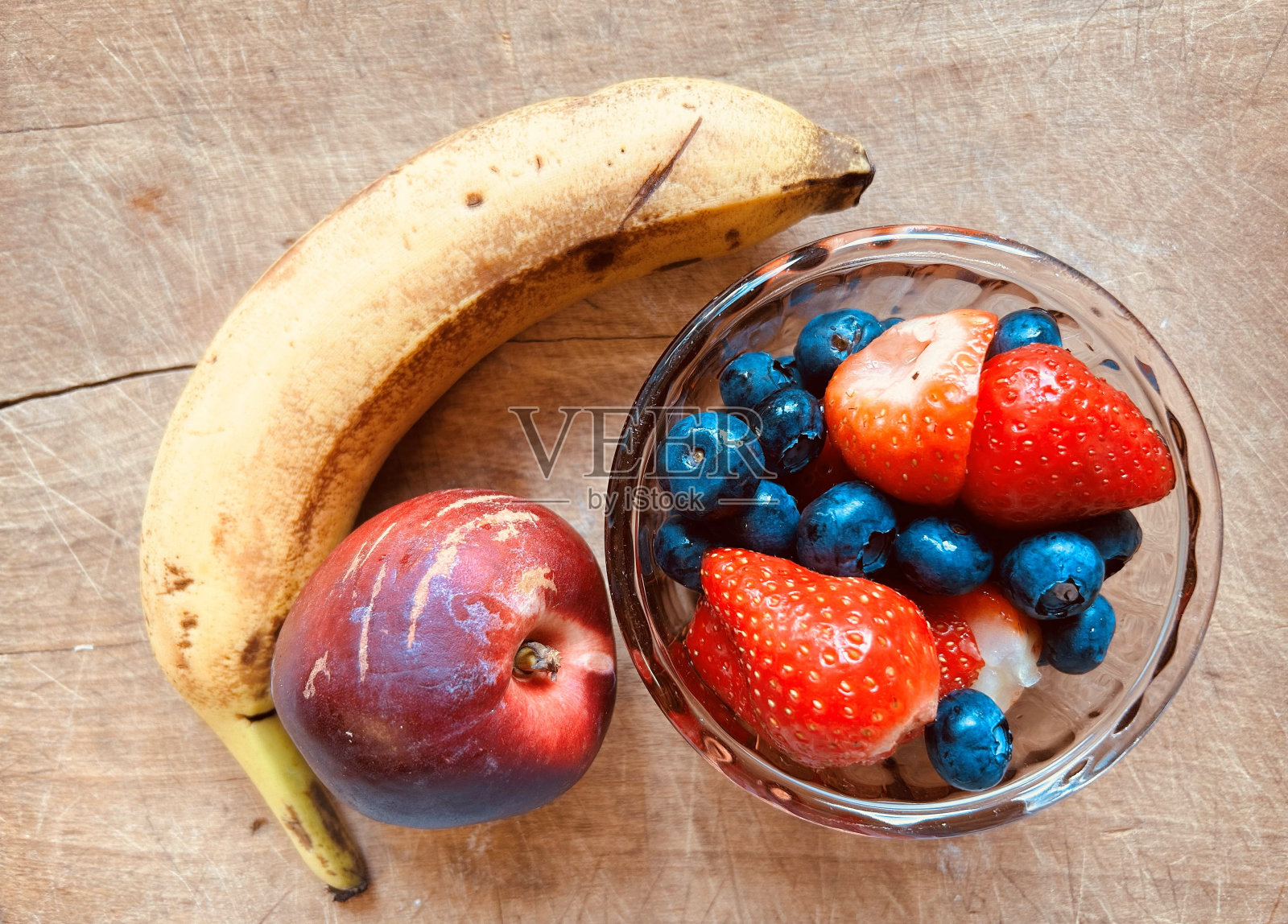 五颜六色，香蕉，油桃，草莓和蓝莓在一个木板上。照片摄影图片