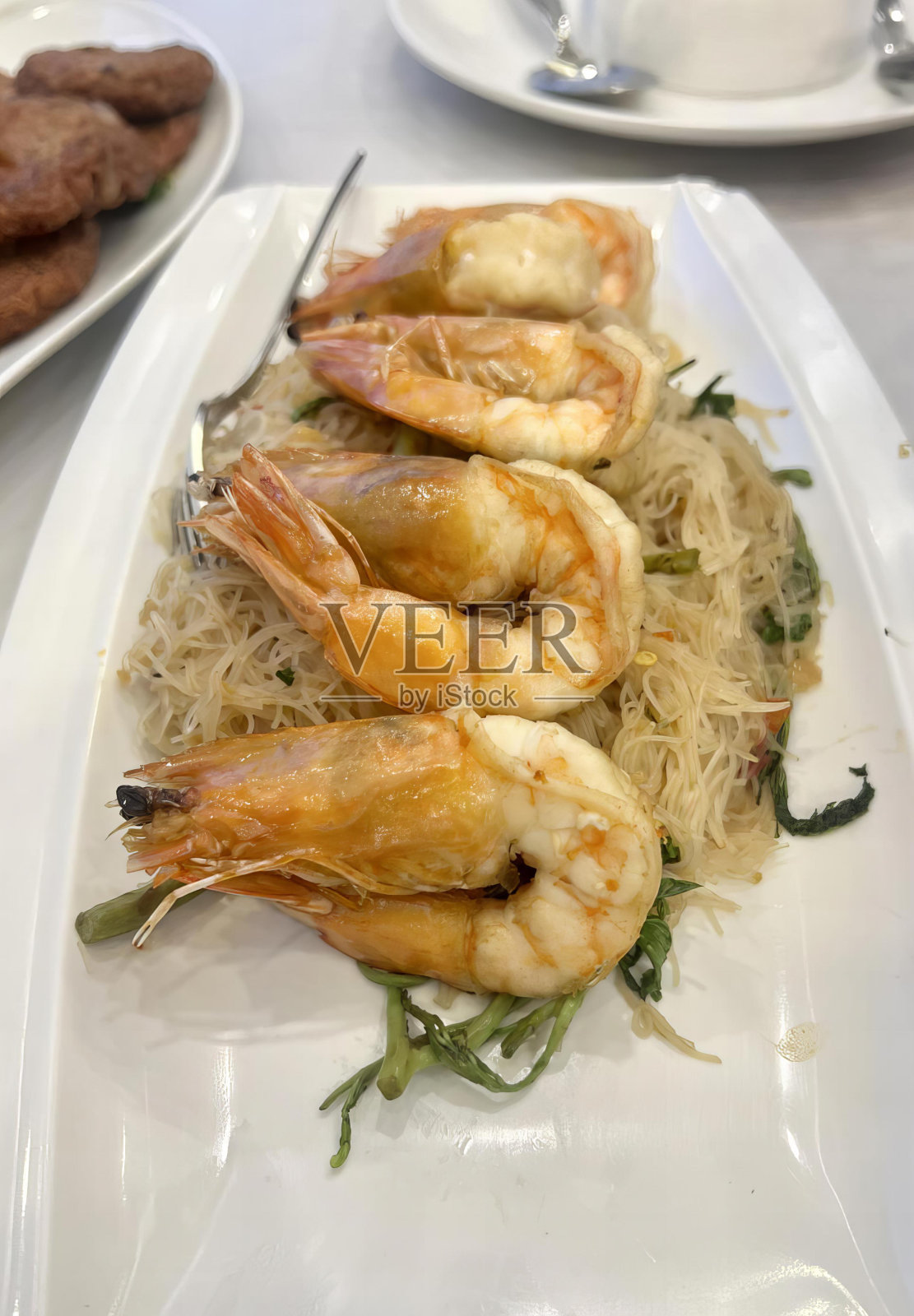 一盘虾和面，旁边是肉，有很多虾在一盘面条和肉的照片。照片摄影图片