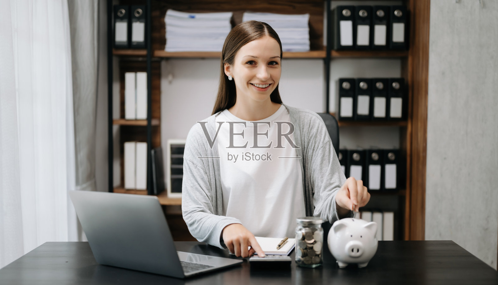 白人妇女把硬币存进存钱罐里，这样生意就能盈利，并为将来存钱。在职规划退休概念照片摄影图片