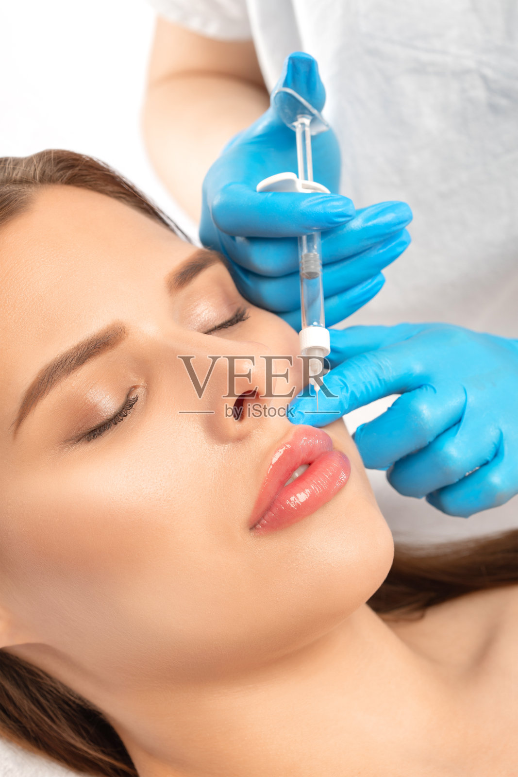 美丽的黑发女人在美容院。美容师在脸上和颧骨上注射抗皱针。美容院的女性美容。照片摄影图片