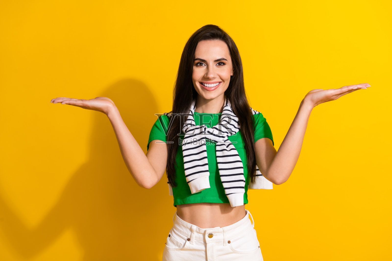 照片中漂亮可爱的女士穿着时髦的衣服，双手张开，对比孤立的黄色背景照片摄影图片