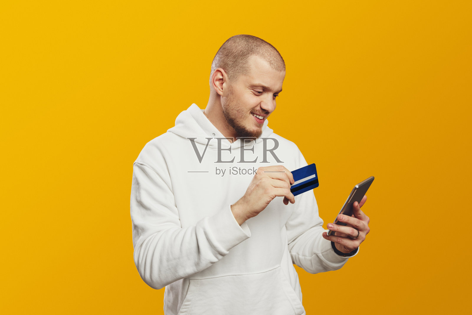 大胡子学生男子手持手机和信用卡，网上购物孤立就黄照片摄影图片