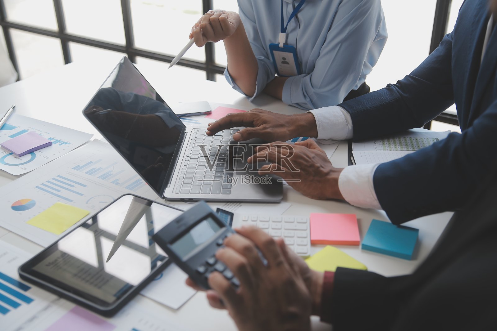 财务分析师在公司会议讨论期间分析了数字平板电脑计划投资项目的商业财务报告，展示了他们成功团队合作的结果。照片摄影图片