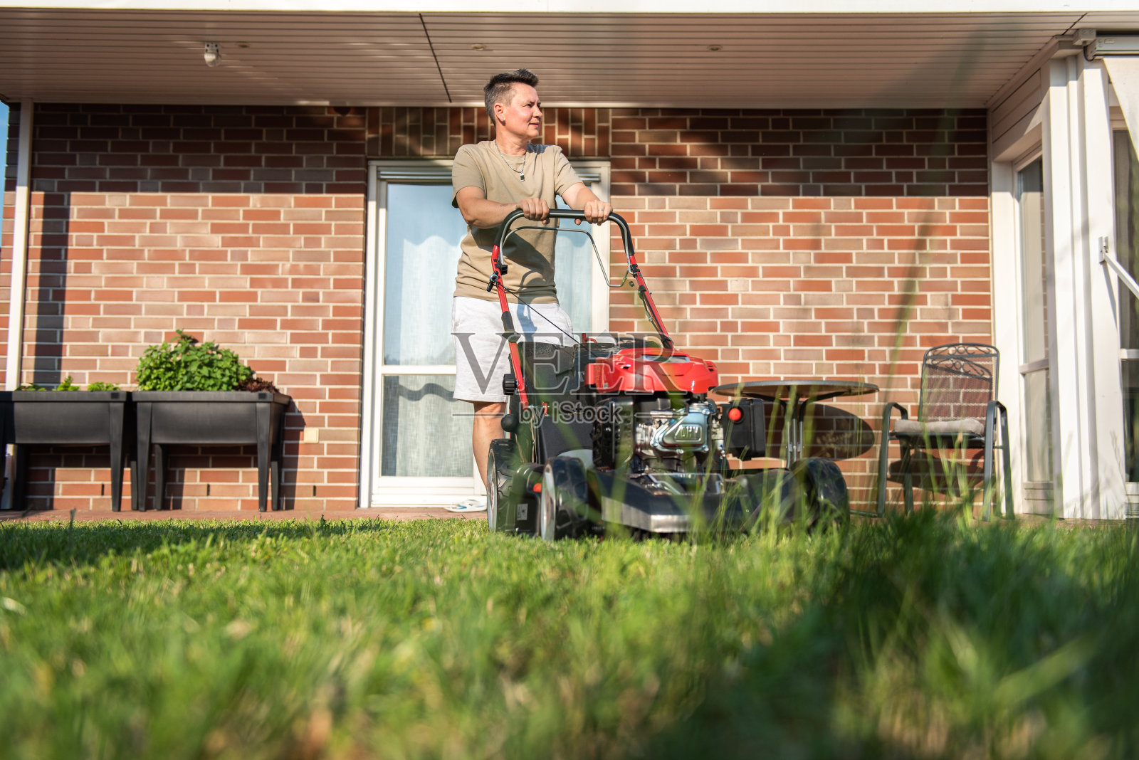 在花园里割草的妇女照片摄影图片