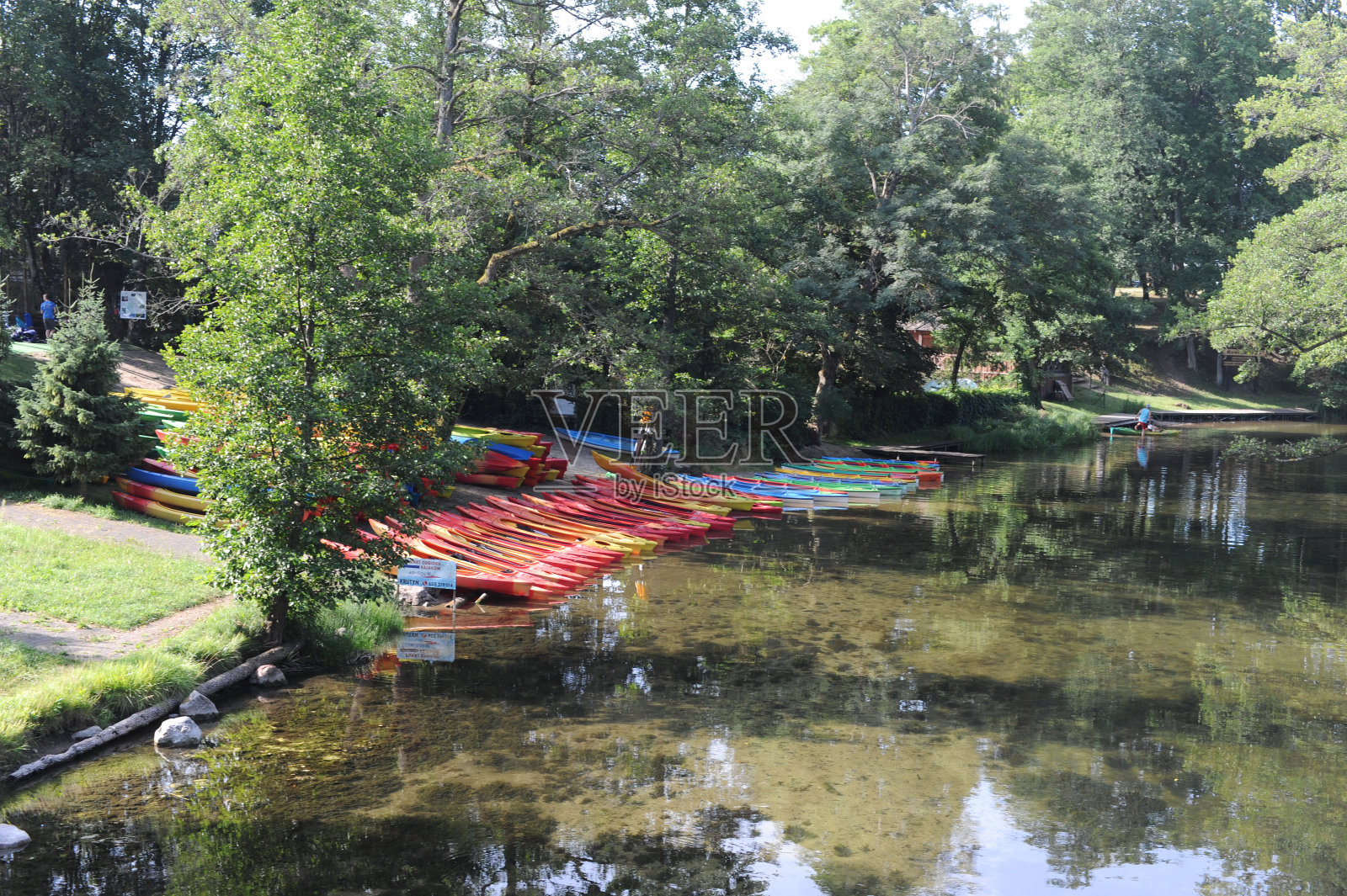 在绿树成荫的夏日，克鲁丁尼亚河岸边的木制码头或码头上的木船照片摄影图片