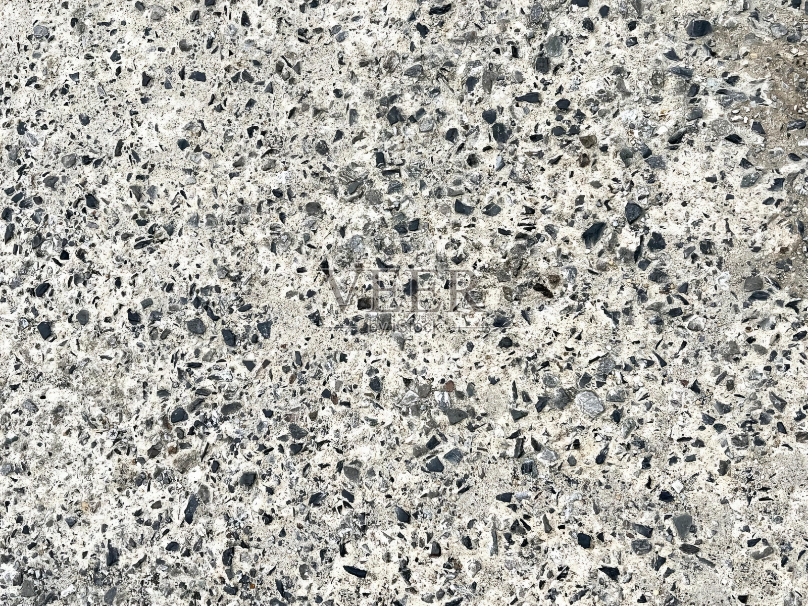 混凝土表面与小岩石的特写摄影，混凝土表面与小黑色和白色岩石的特写。照片摄影图片