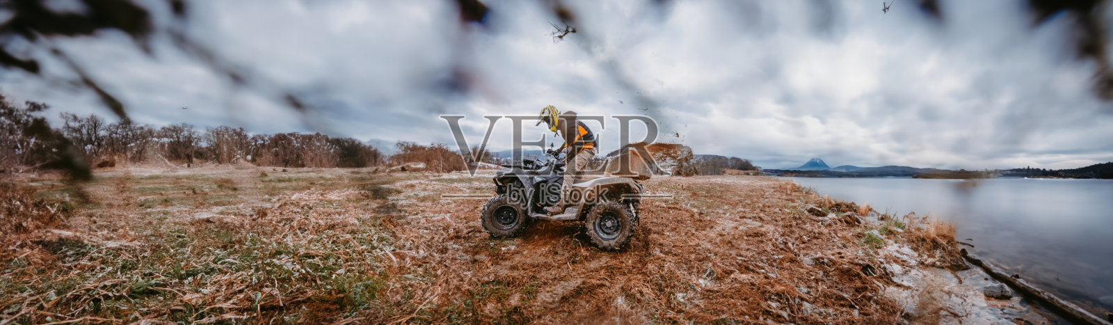 一名男子无畏地享受着乘坐ATV Quad穿越危险的雪地地形的冒险之旅，拥抱着充满挑战的山区景观的刺激和兴奋照片摄影图片