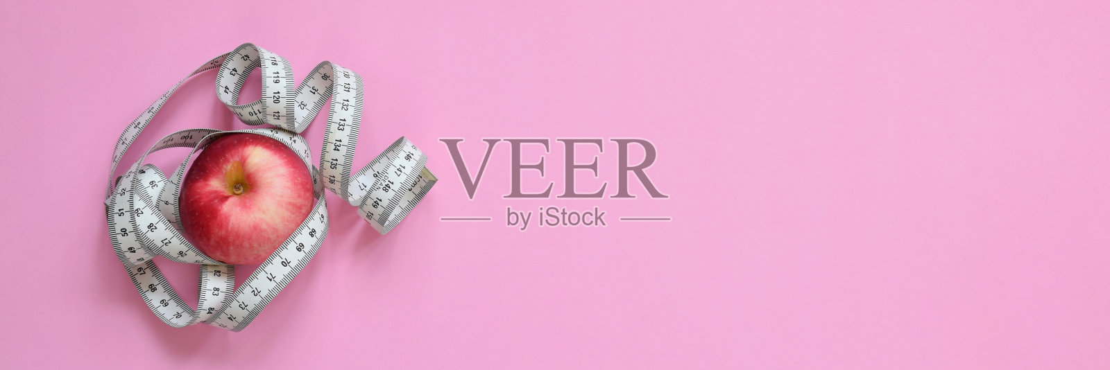 红苹果与卷尺在粉红色的背景照片摄影图片