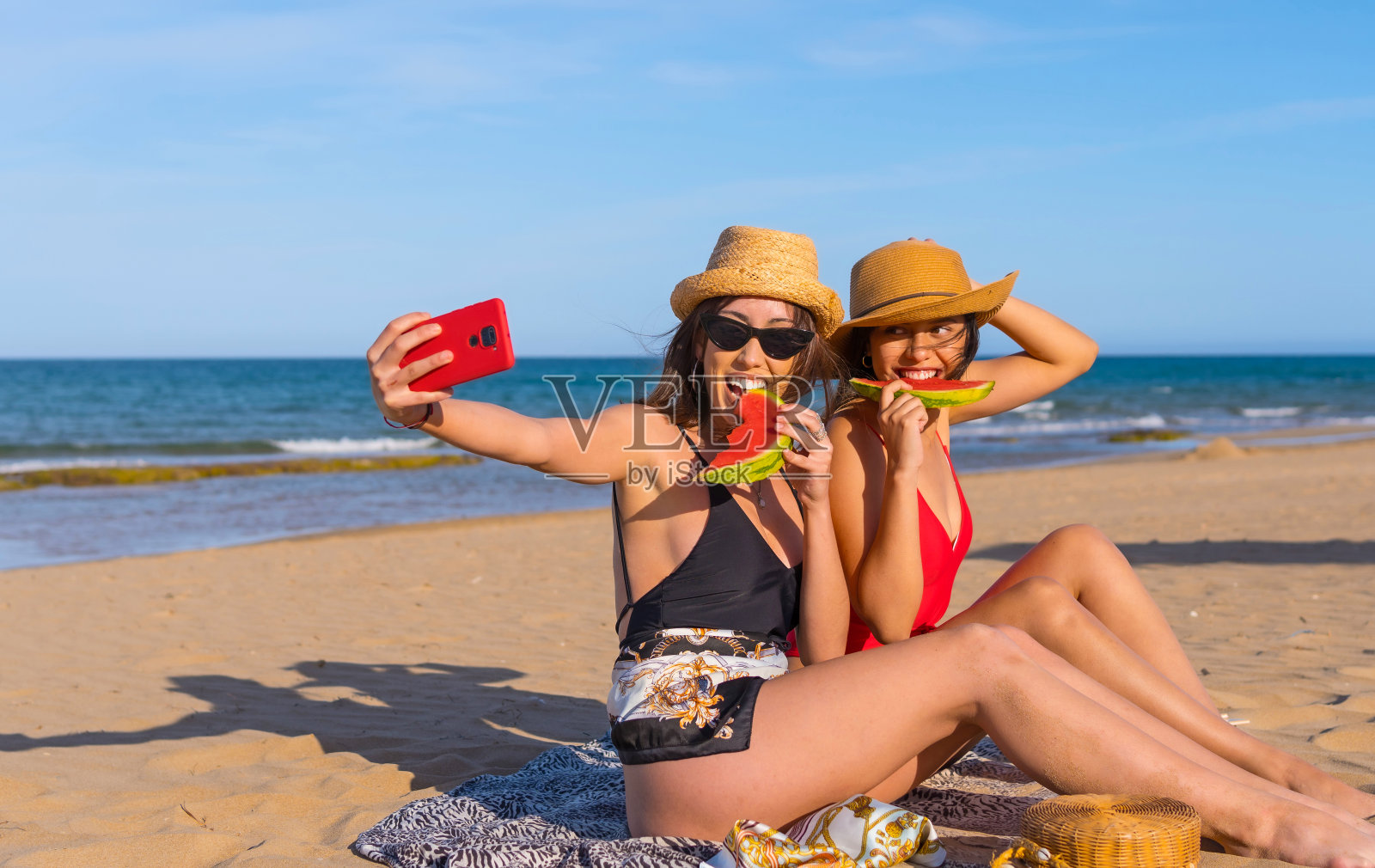 朋友们夏天在沙滩上吃着以海为背景的西瓜，自拍微笑照片摄影图片