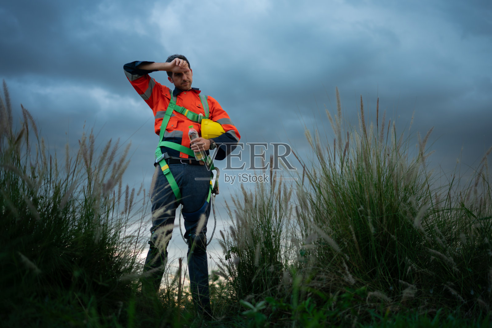 一个年轻人的肖像，在风力发电机领域工作，穿着安全背心，下班后放松时间的概念照片摄影图片
