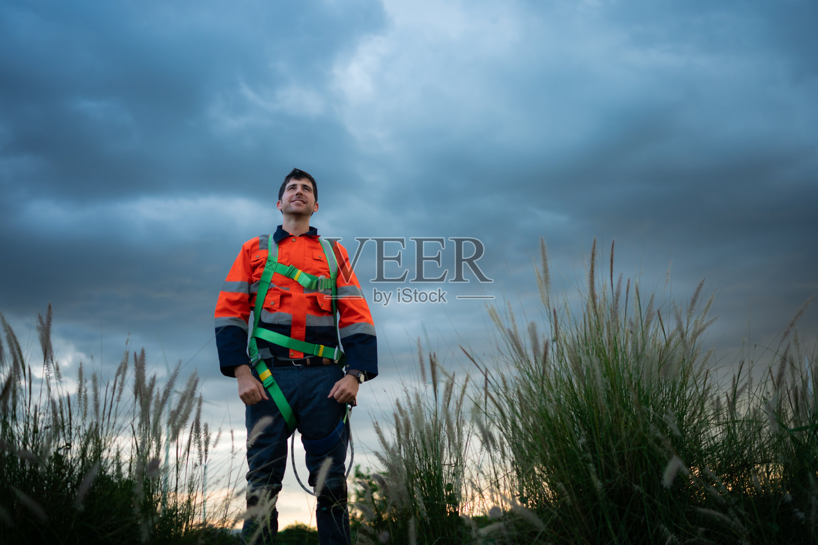 一个年轻人的肖像，在风力发电机领域工作，穿着安全背心，下班后放松时间的概念照片摄影图片