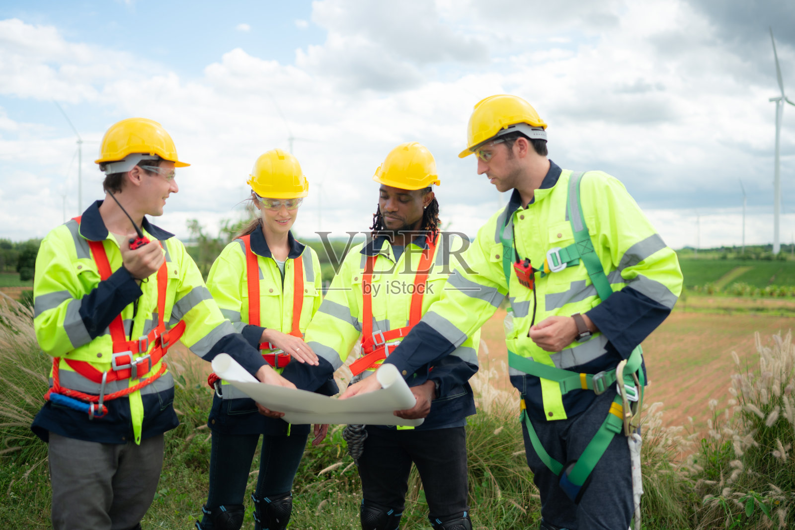 一群工程师和技术人员正在讨论和研究以风力涡轮机为背景的蓝图照片摄影图片