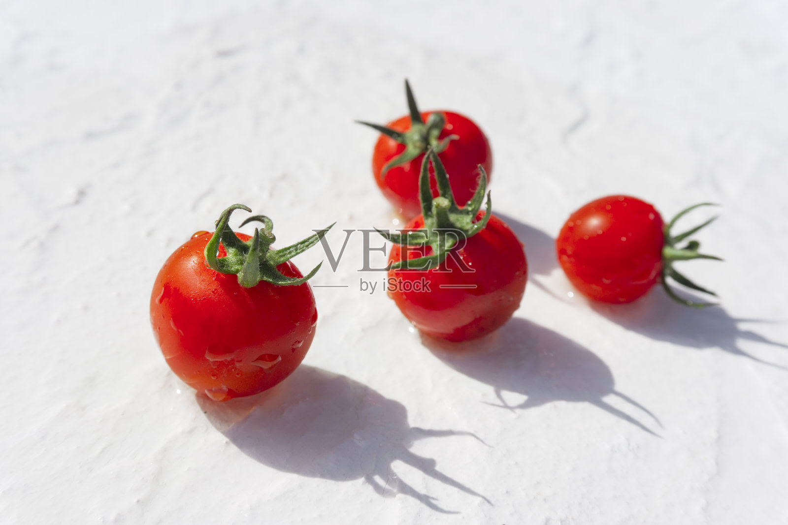 白色粉刷板上有水滴的西红柿。照片摄影图片