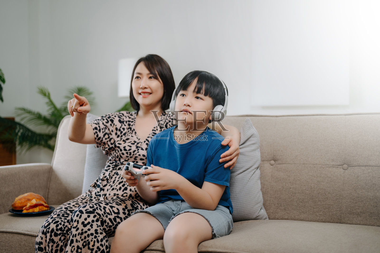 妈妈和儿子一起坐在家里房间的沙发上玩电脑游戏照片摄影图片