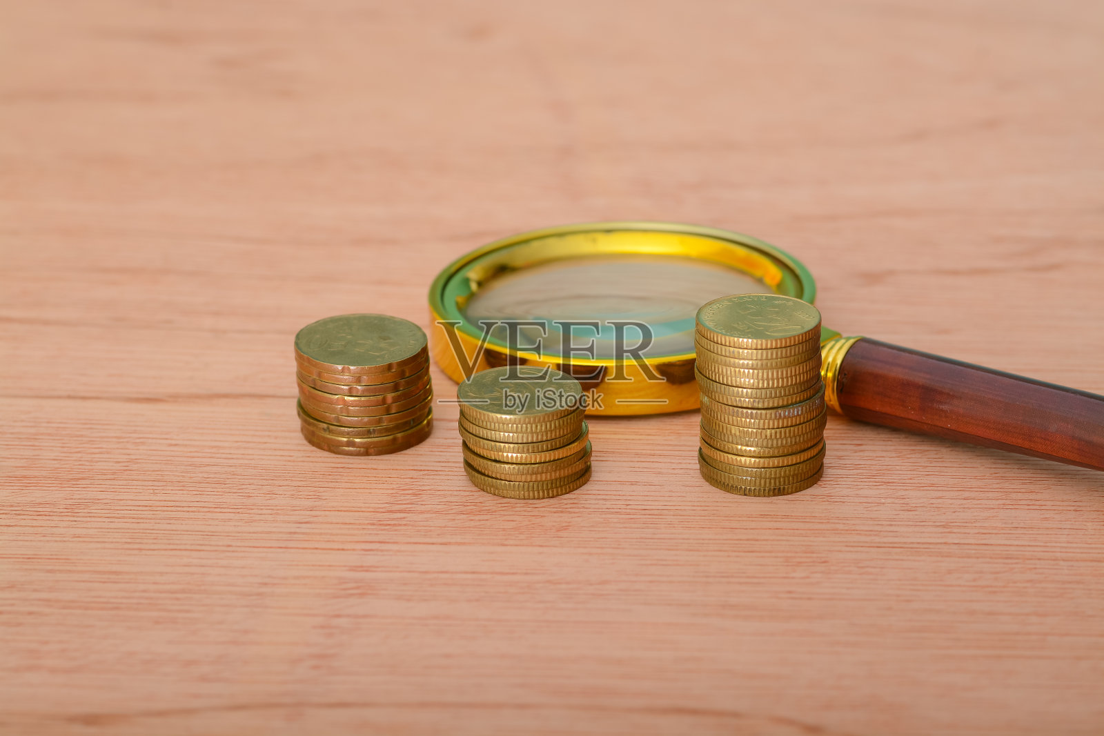 放在硬币床上的放大镜，象征着金融发展、银行账户、统计分析、投资研究和股票交易。照片摄影图片