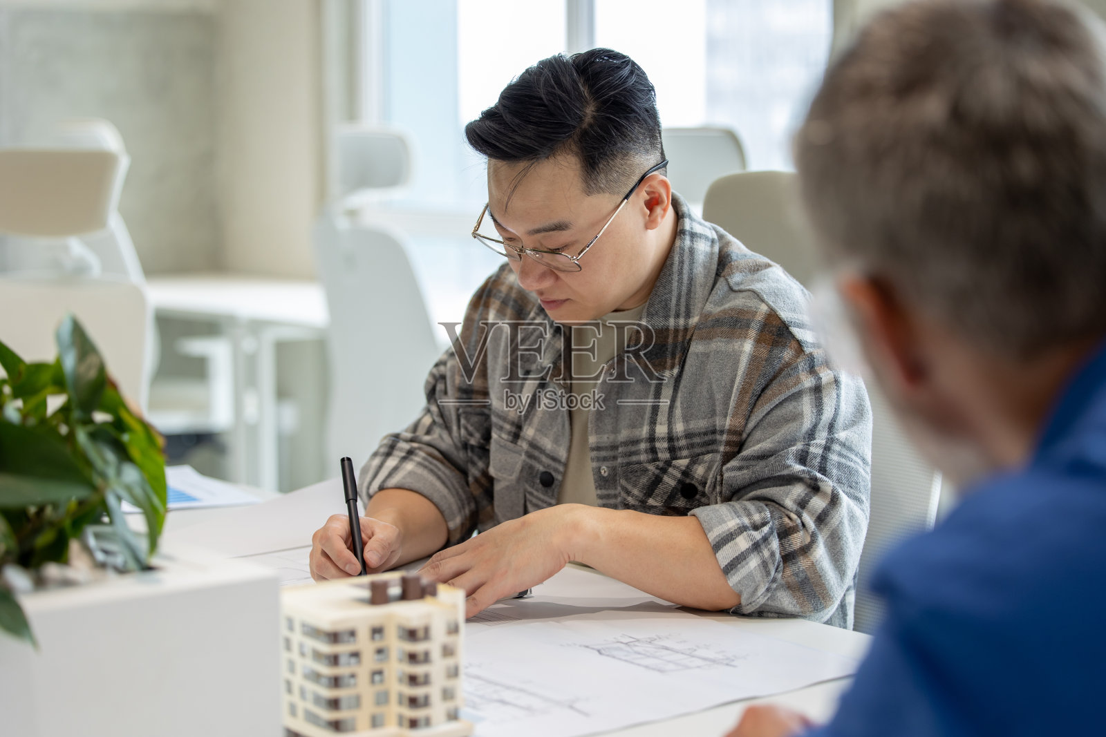 男建筑师正在绘制现代住宅的蓝图。照片摄影图片