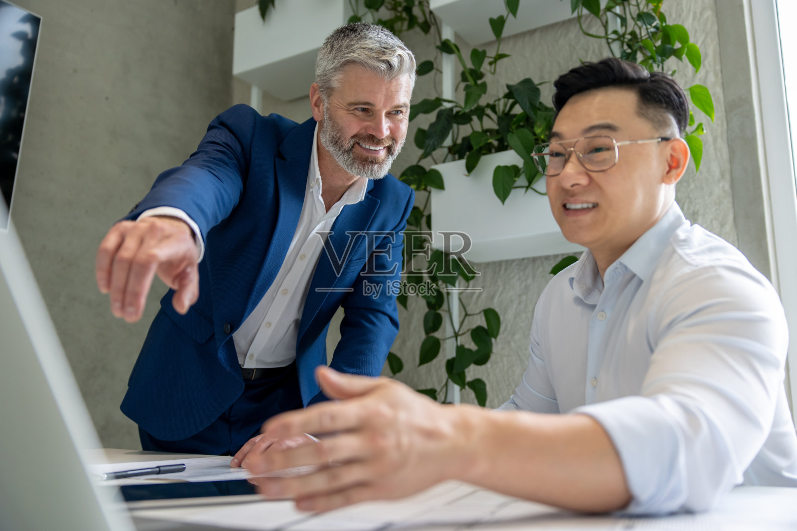 建筑师在办公室用笔记本电脑和工作的蓝图建模新房子一起。照片摄影图片