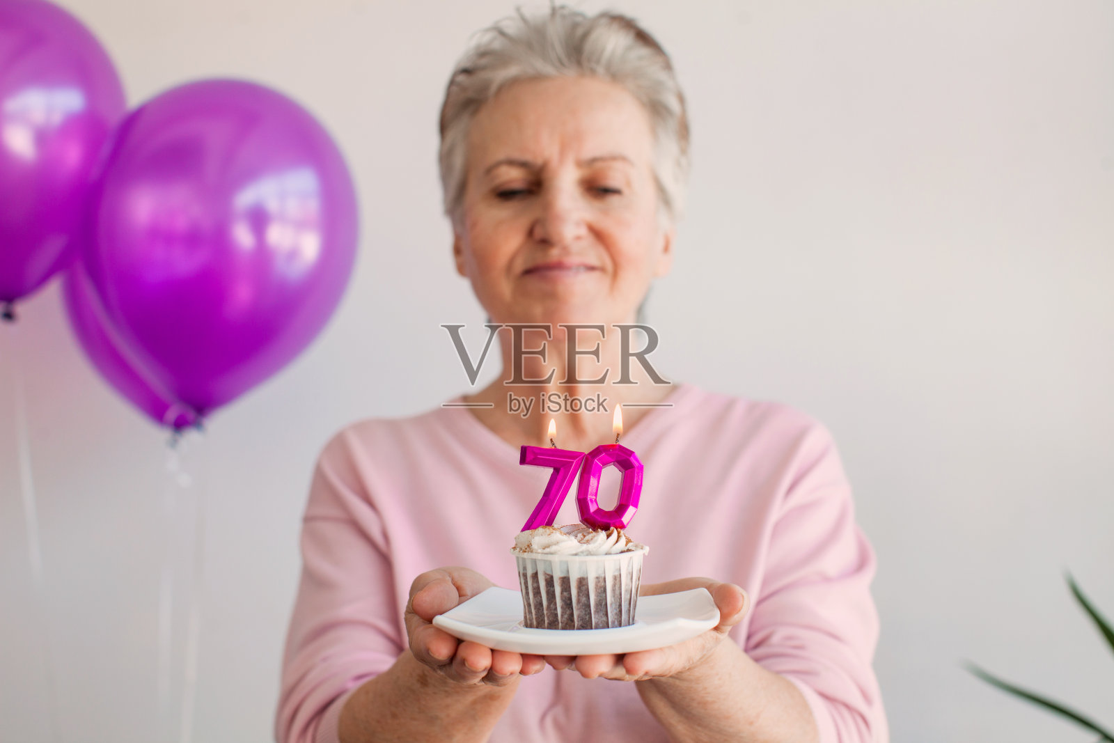 70多岁的老人微笑着，凉爽快乐的女人手持生日蛋糕和蜡烛照片摄影图片