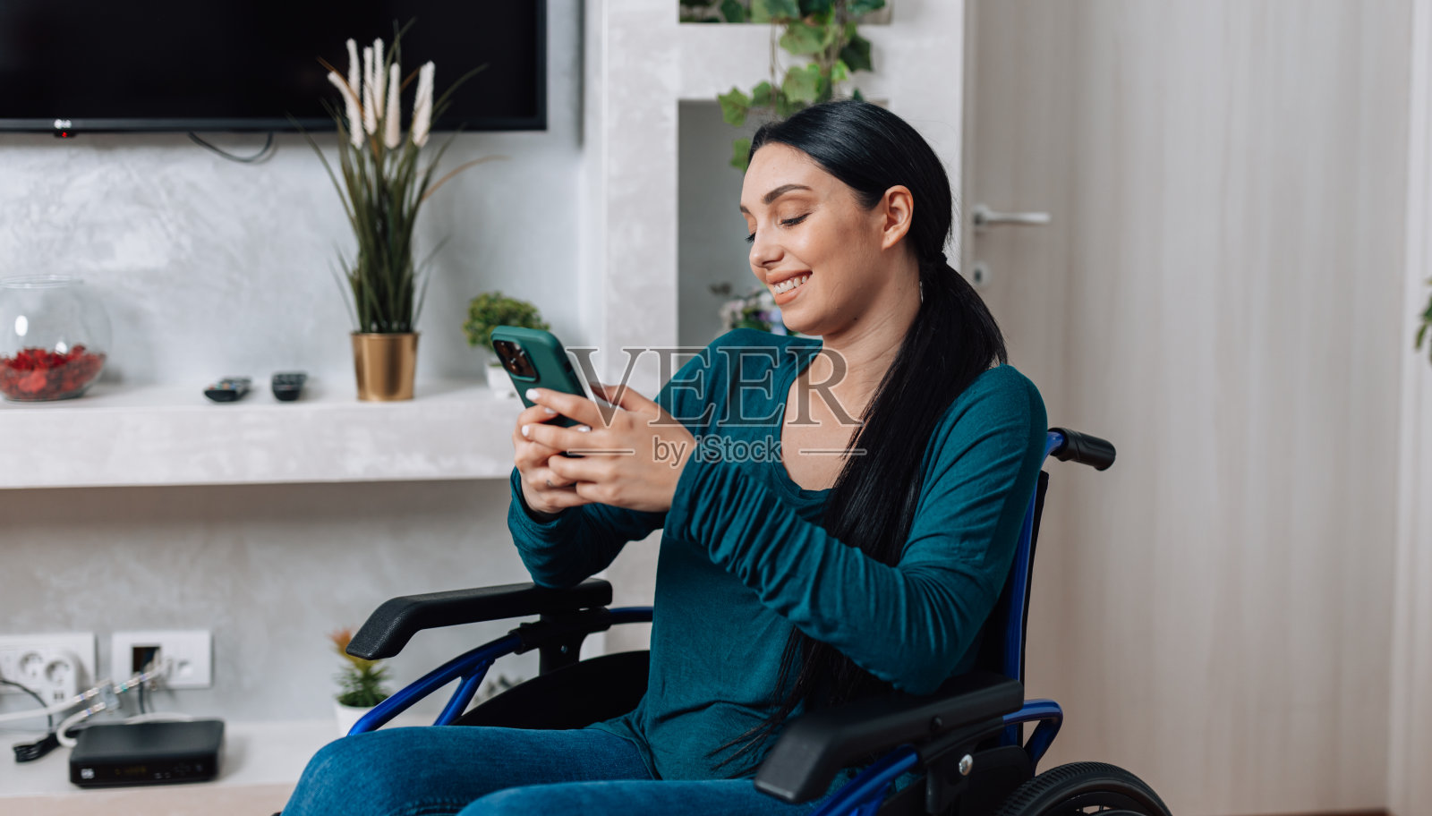 坐在轮椅上的年轻女子抱着她的移动设备照片摄影图片