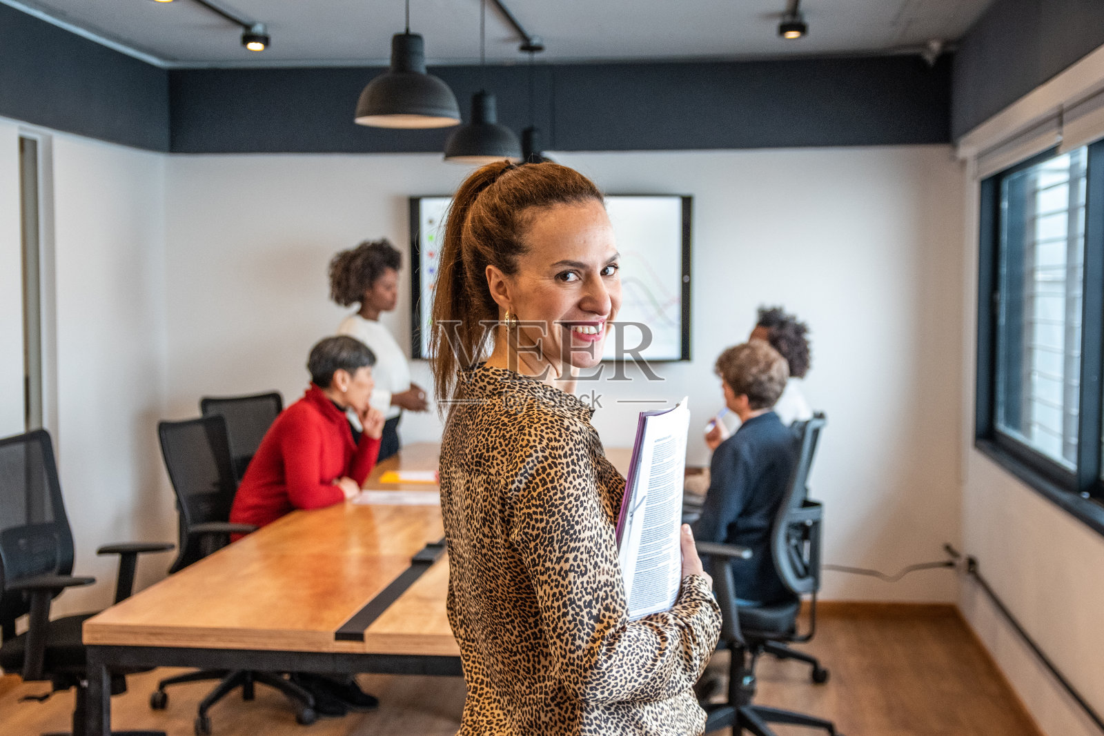 一个成熟的女人在办公室拿着文件/教科书的肖像照片摄影图片