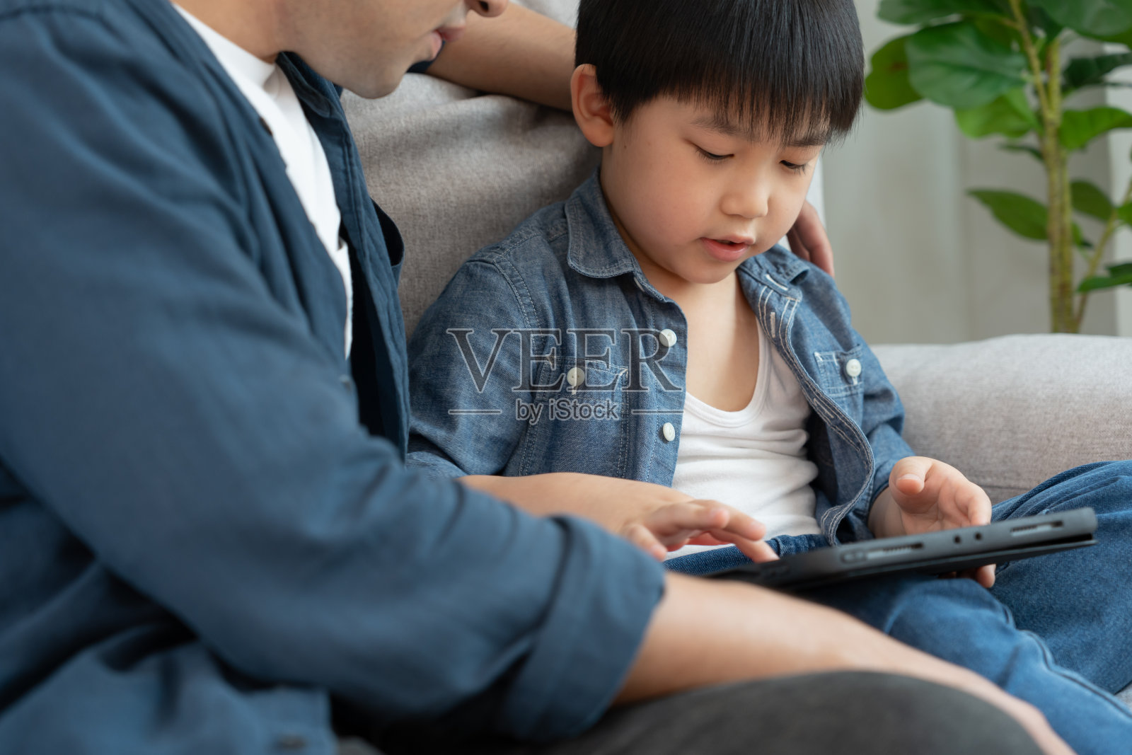 快乐的单亲爸爸和小男孩玩着用平板电脑教书。家里的人都很高兴，很兴奋。父子共度时光，好爸爸，戒瘾，处理，控制照片摄影图片