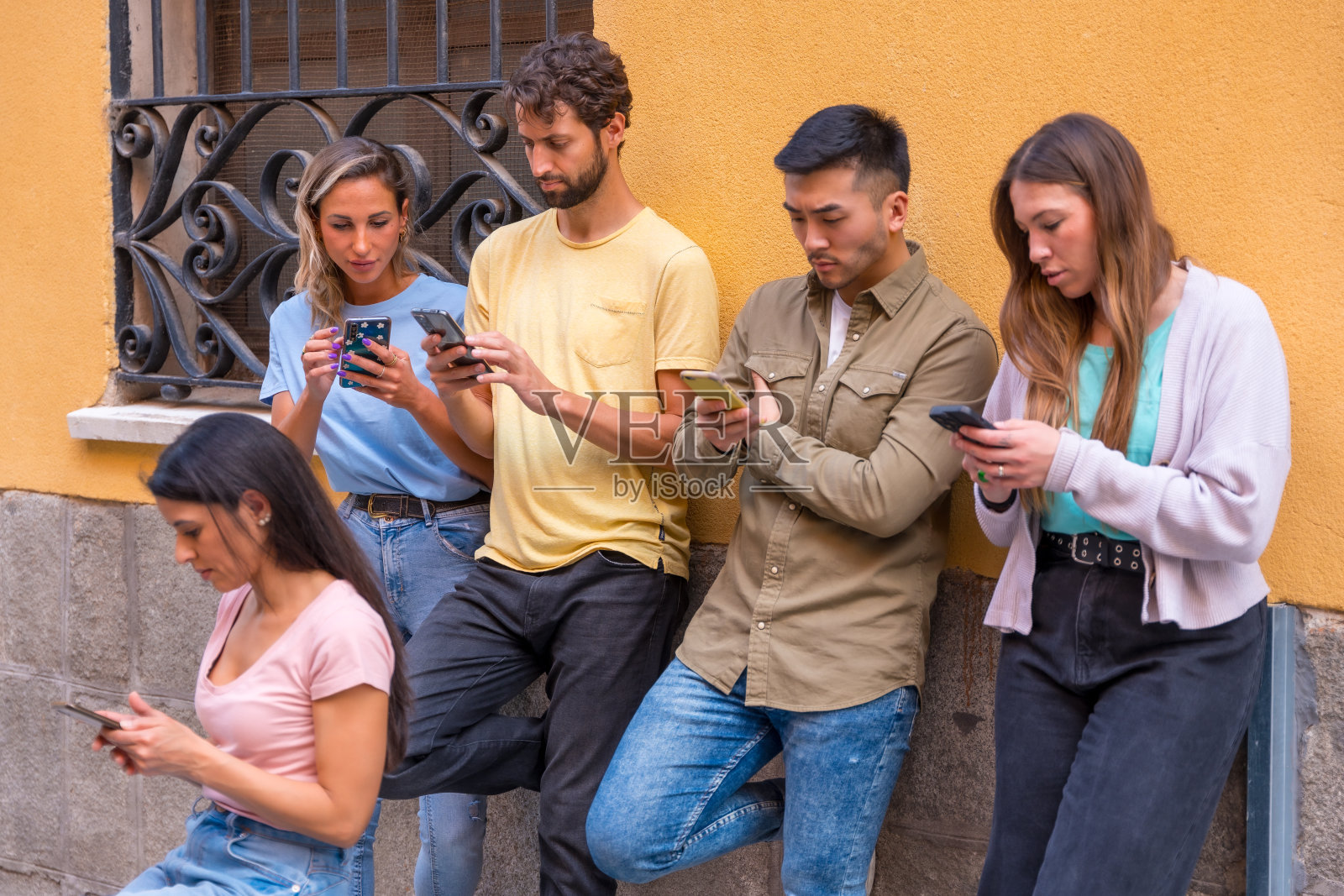 一群多种族的朋友在城市里认真地看着手机，概念青年迷上了手机照片摄影图片