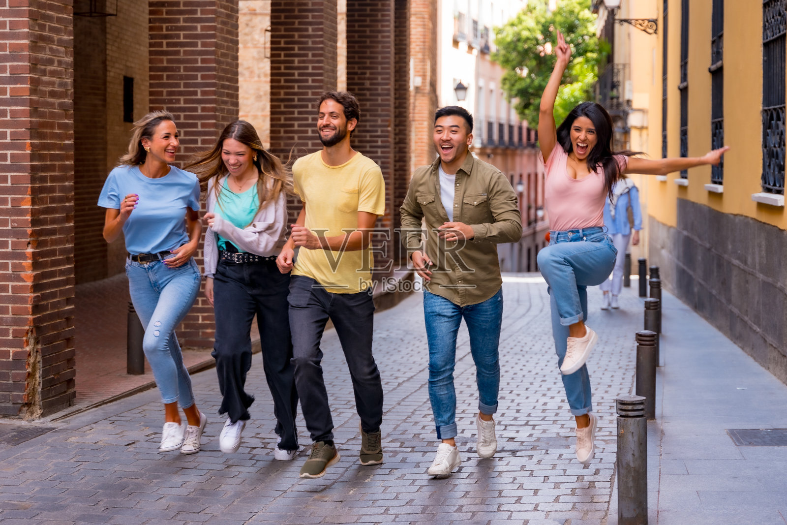 一群多种族的朋友在城市里拥抱，微笑，跳跃，友谊的概念与男孩和女孩照片摄影图片