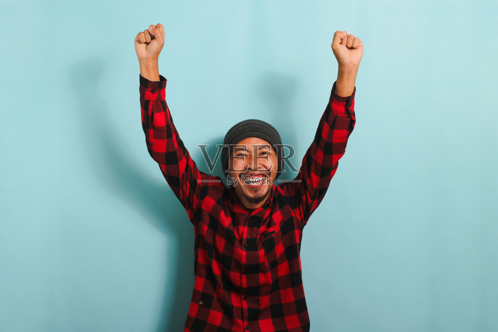 兴奋的年轻亚洲男子欢欣鼓舞，用拳头表示同意，孤立在蓝色背景上照片摄影图片