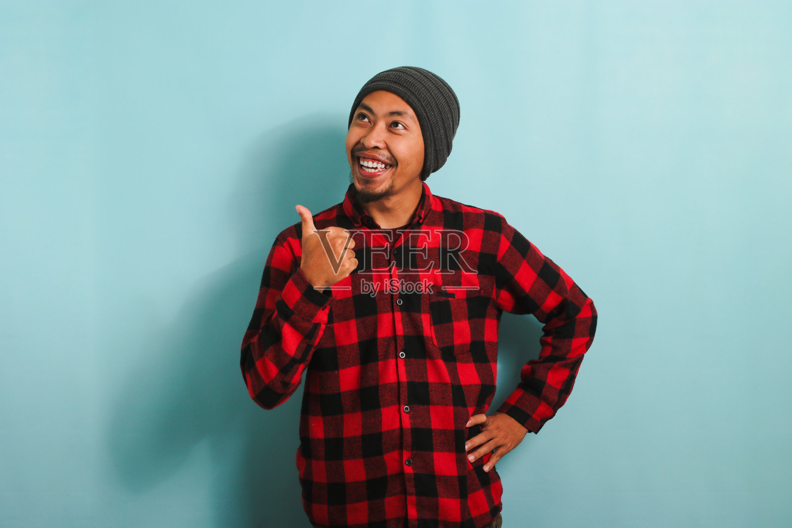 年轻的亚洲人正用手指着旁边空荡荡的拷贝空间，孤立在蓝色的背景上照片摄影图片