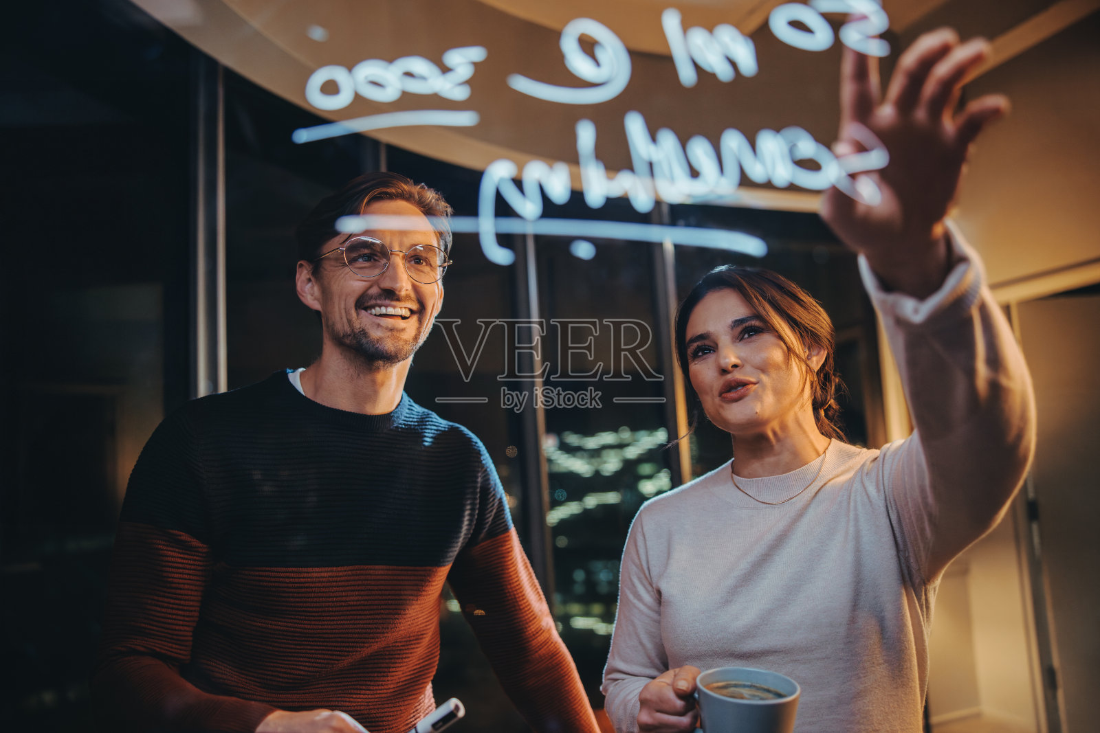 两个商人在一间玻璃墙办公室里开着深夜的商务会议照片摄影图片