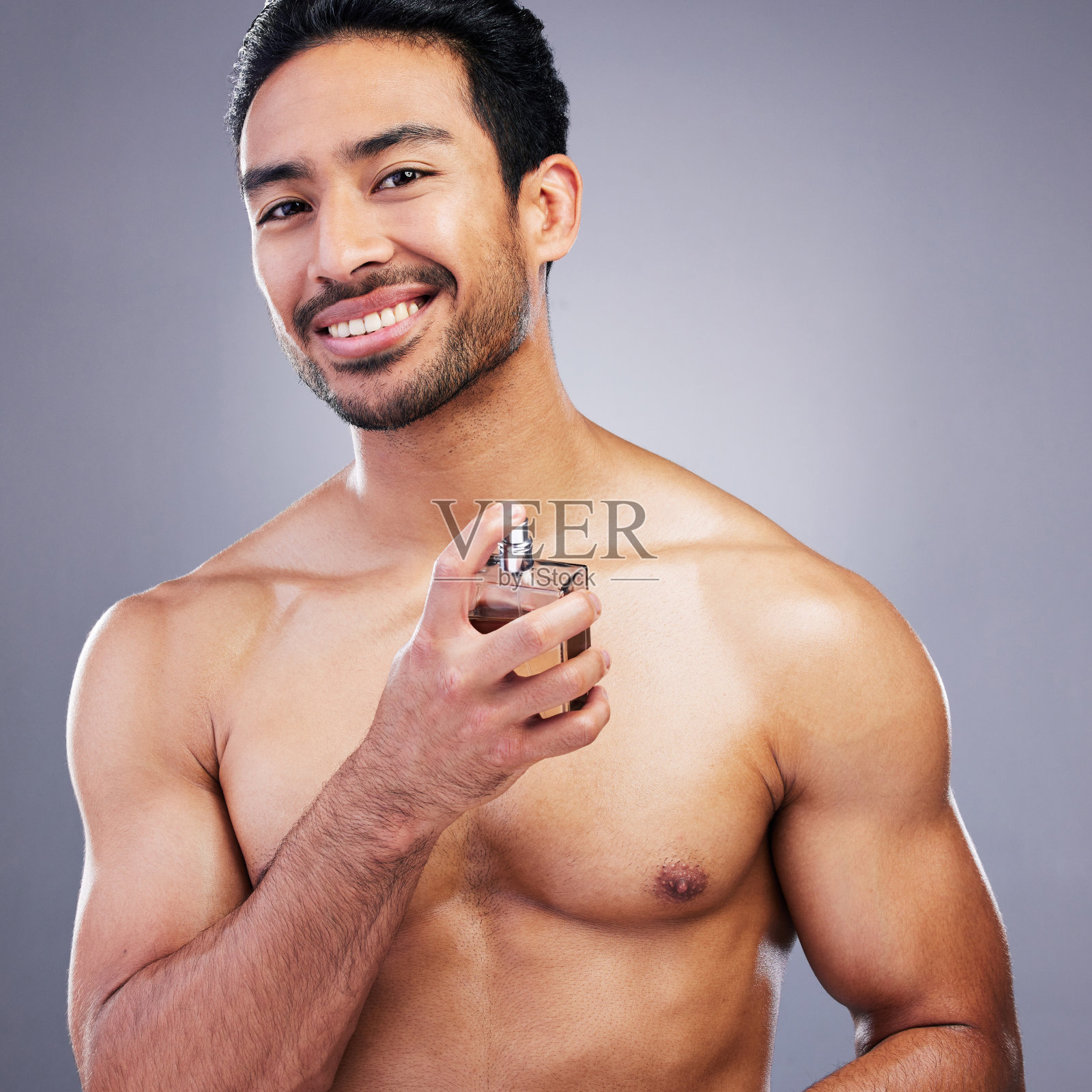 肖像，化妆品或快乐的男人用古龙水美容或自我护理孤立的工作室背景。健康，人或亚洲模特用奢侈的身体香水喷雾和香水瓶修饰照片摄影图片