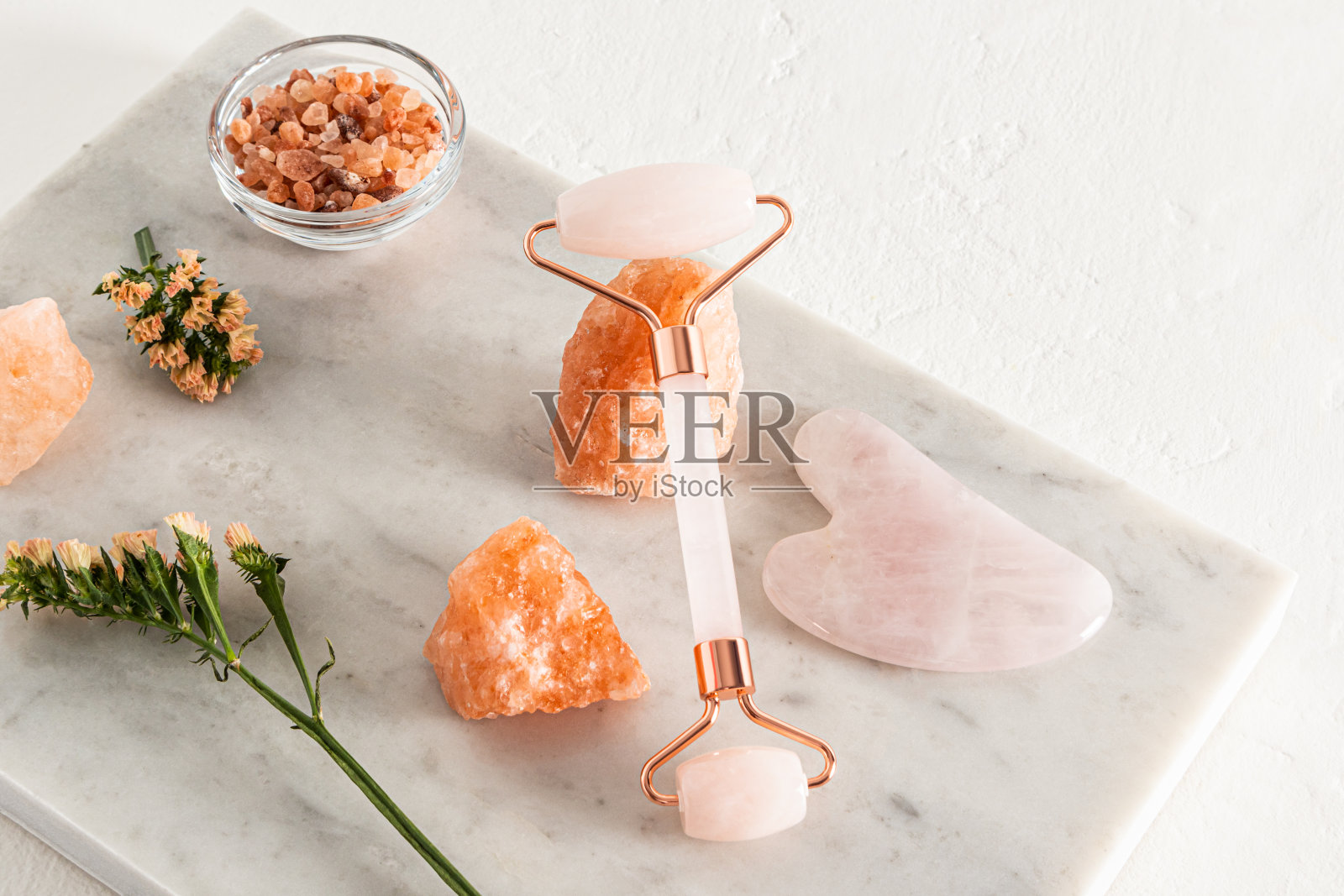 一个石英滚筒按摩器靠在一块盐上。水粉画刮刀。在碗里放浴盐。一套用于按摩、水疗、放松的化妆品。自然。照片摄影图片
