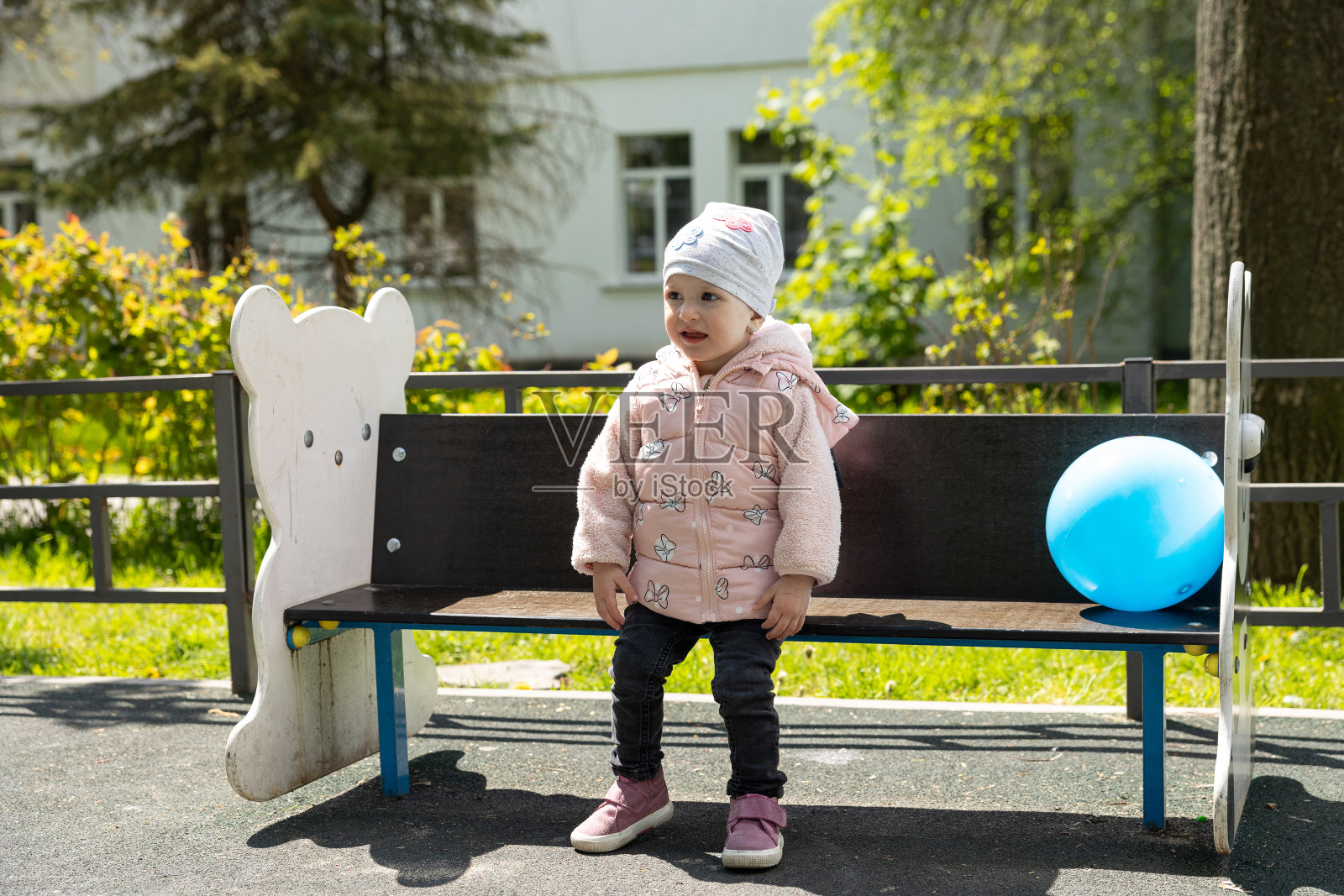 这个孩子坐在公园里的儿童长凳上。照片摄影图片